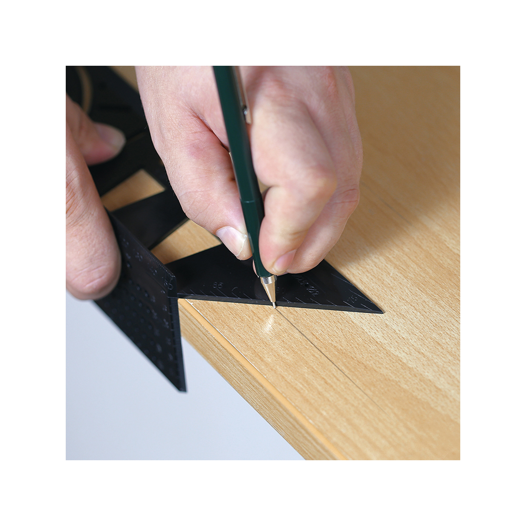 Eine Person verwendet ein schwarzes Lineal und einen Stift, um eine Linie auf einer Holzoberfläche zu markieren. Der Stift ist grün.