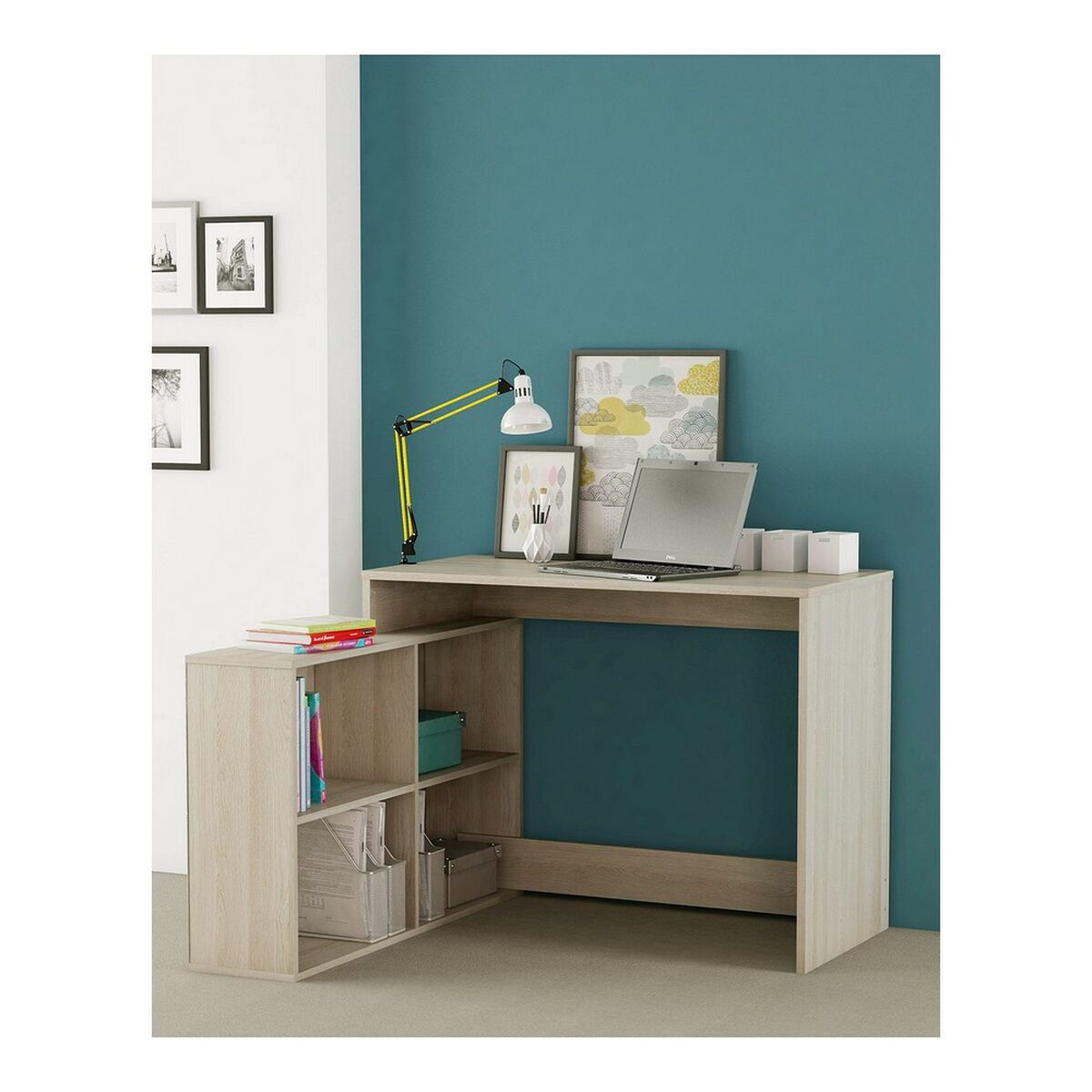 Ein Holzschreibtisch mit Laptop, Lampe und Bildern. Der Schreibtisch hat Regale mit Büchern und Boxen. Der Hintergrund ist teal.