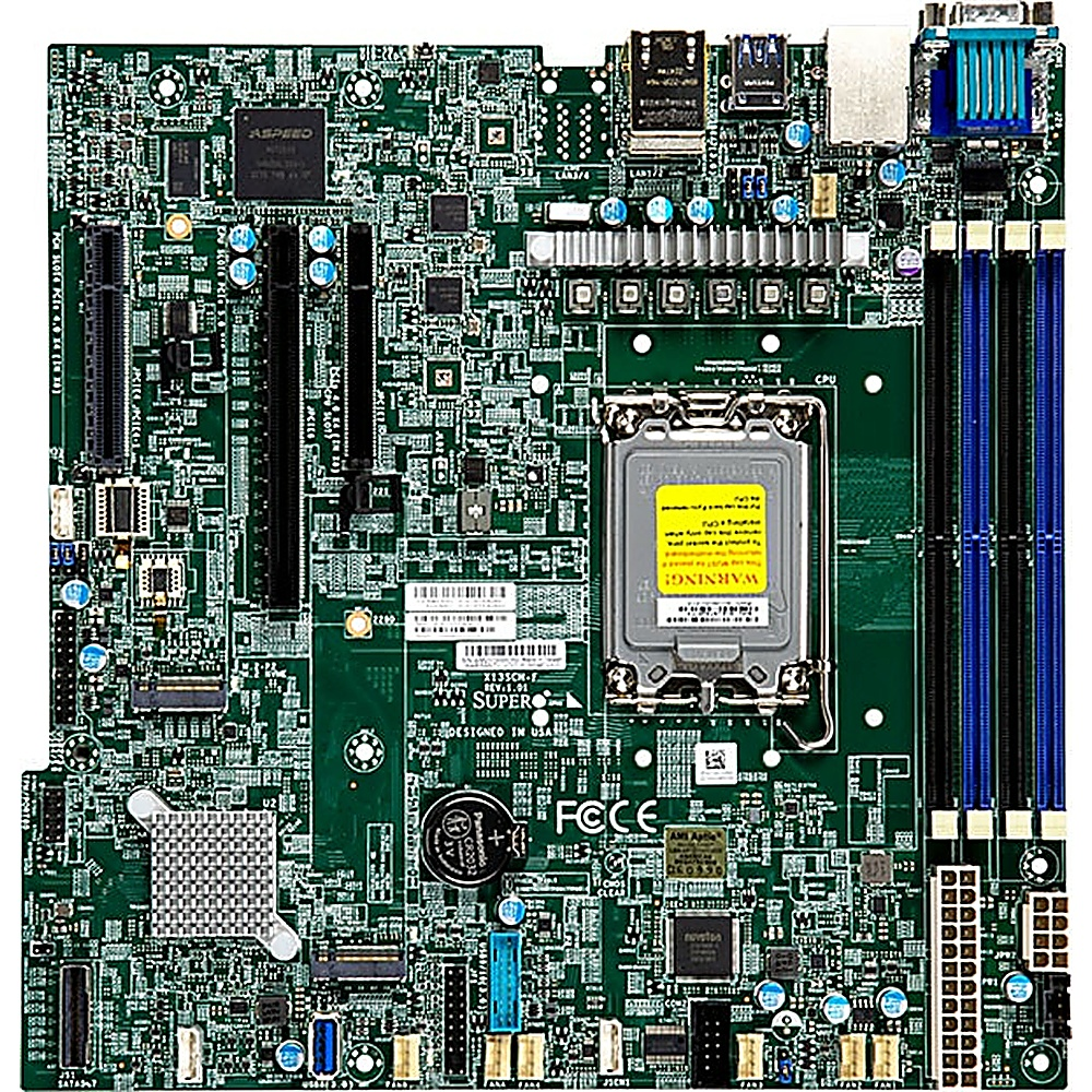 Una scheda madre di computer verde con vari componenti, tra cui chip, slot e connettori. Il socket della CPU è etichettato con un adesivo di avvertimento.
