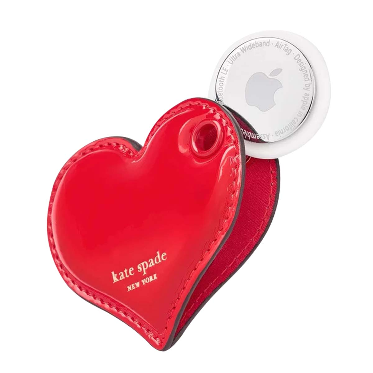 Ein rotes herzförmiges Kate Spade-Etui enthält ein Apple AirTag. Das AirTag ist weiß mit einem silbernen Apple-Logo. Das Etui ist glänzend.