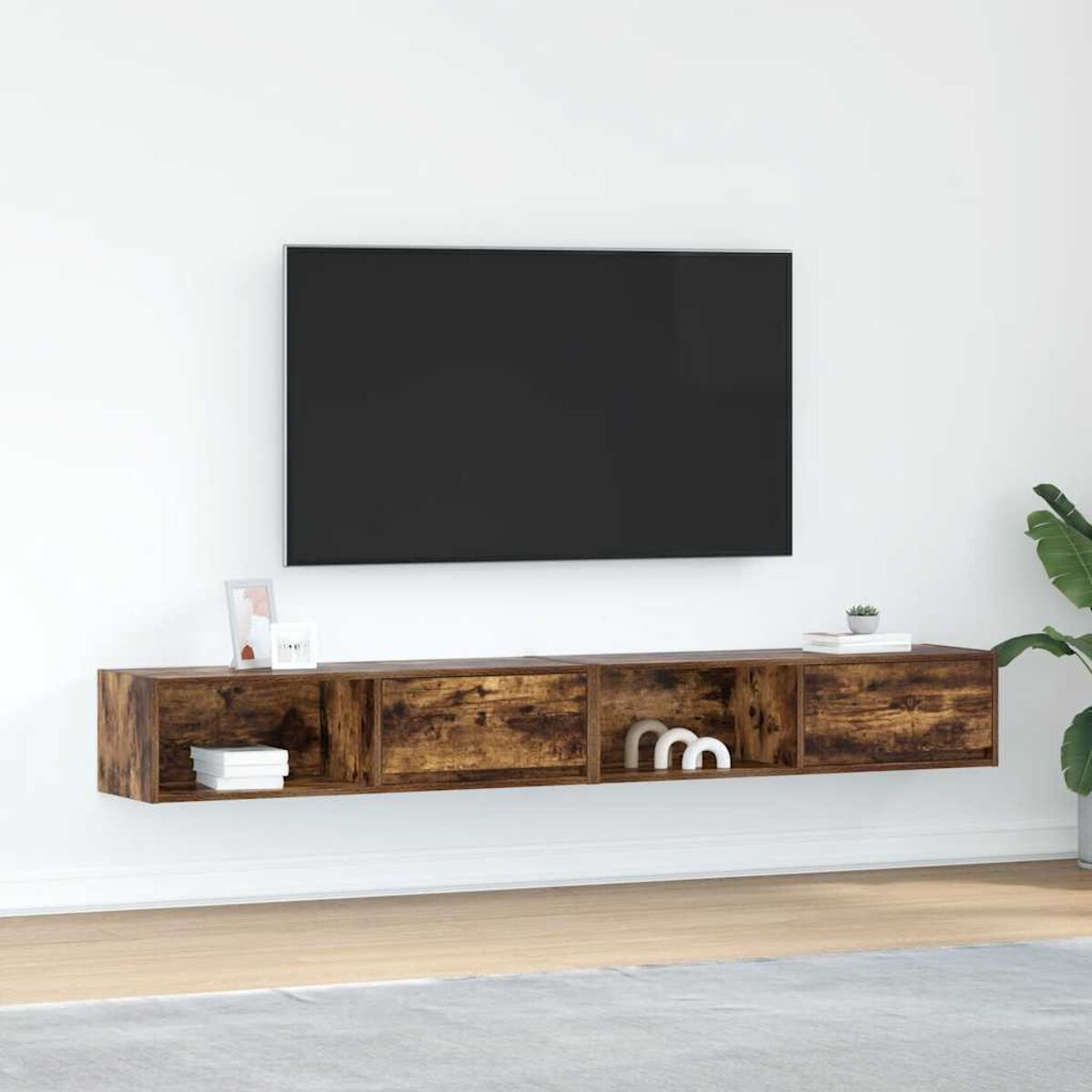 Ein Fernseher über einem Holzregal mit Dekoration. Die Wand ist weiß. Rechts eine Pflanze und heller Boden.