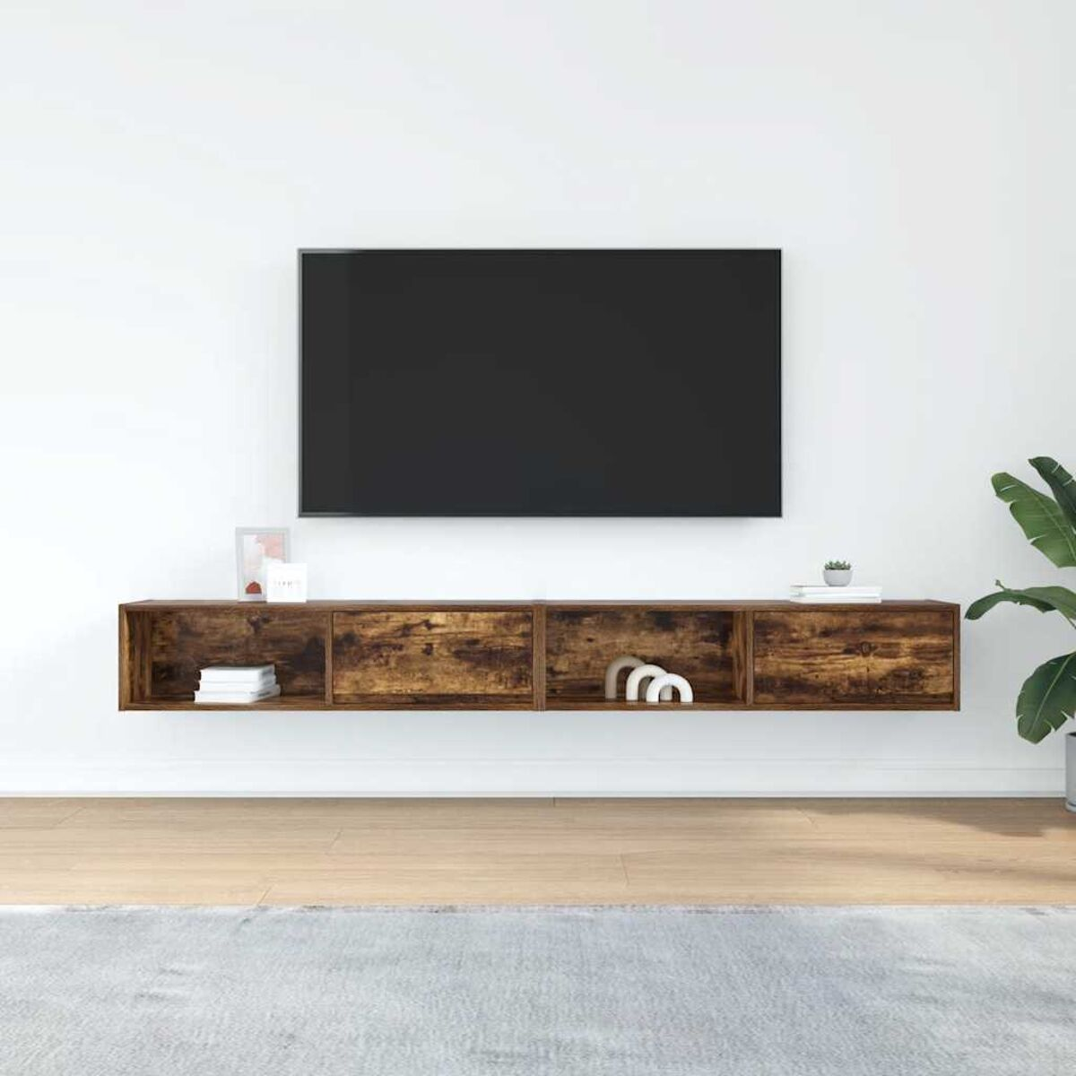 Ein Wohnzimmer zeigt einen Fernseher an der Wand über einem Holzregal. Darunter ein Teppich und rechts eine Pflanze.