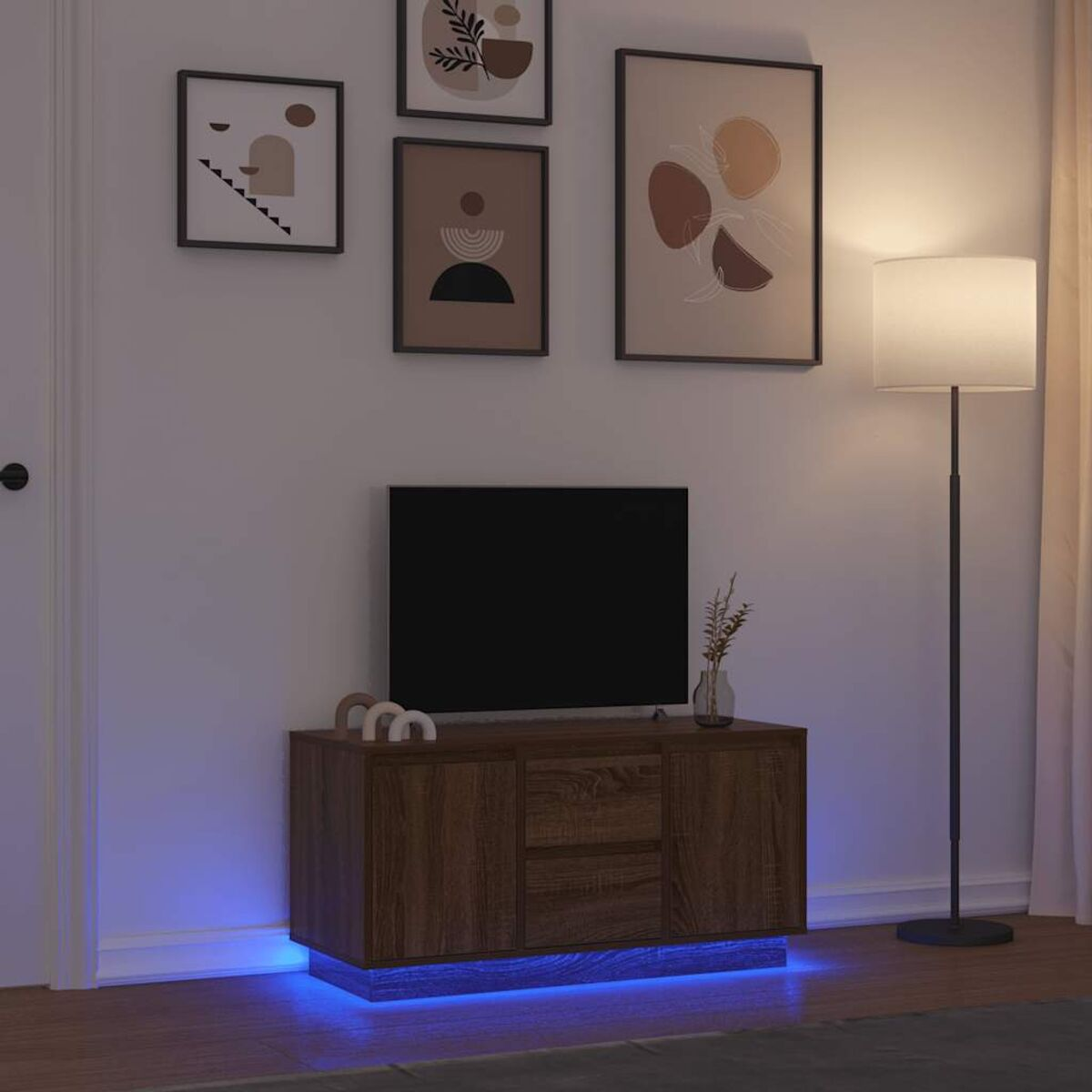Ein Fernsehschrank aus Holz mit einem schwarzen Fernseher, einer Stehlampe, Bildern an der Wand und blauer Beleuchtung.