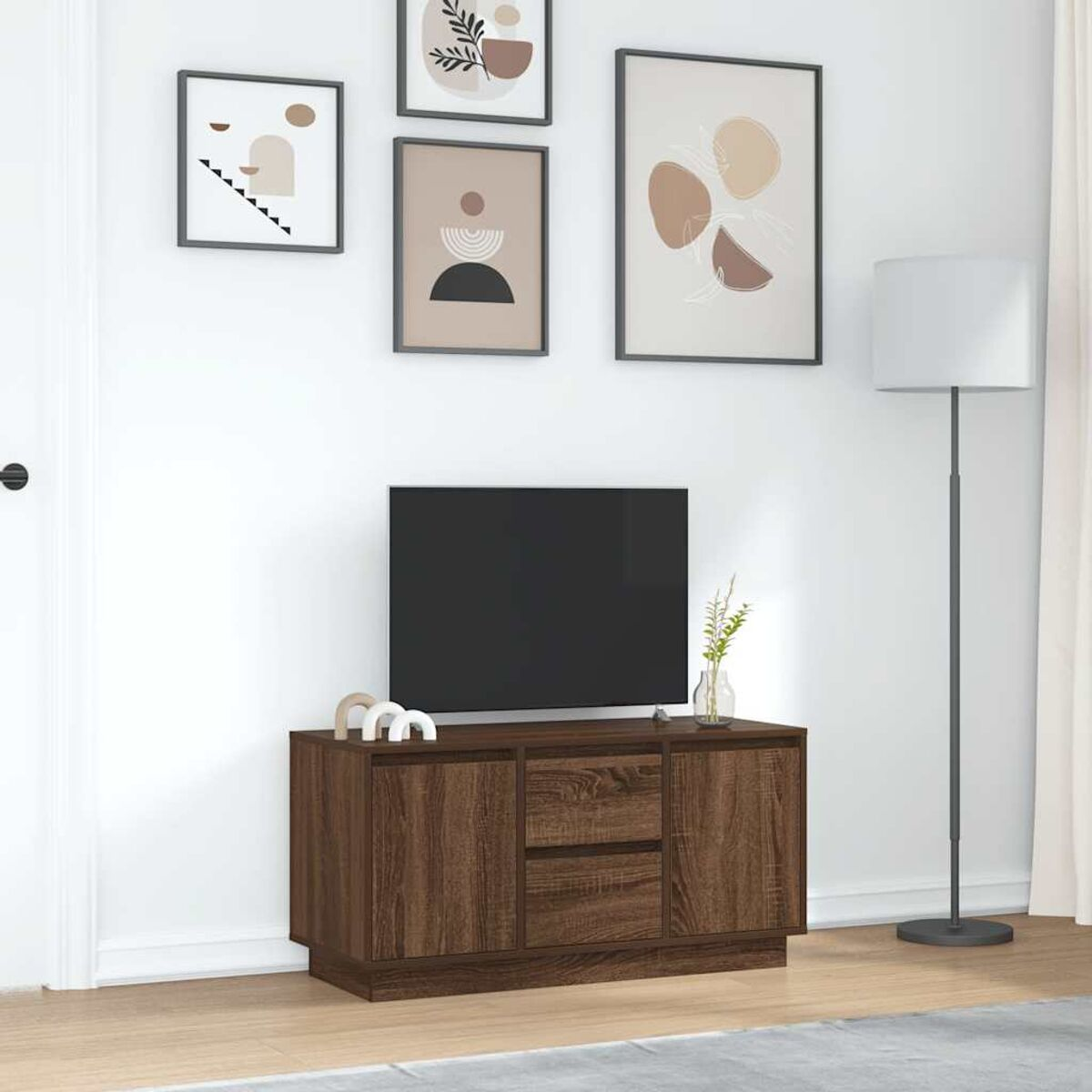 Ein Raum mit Fernseher auf einem braunen Schrank und abstrakten Kunstdrucken. Eine Lampe steht neben einem weißen Vorhang.