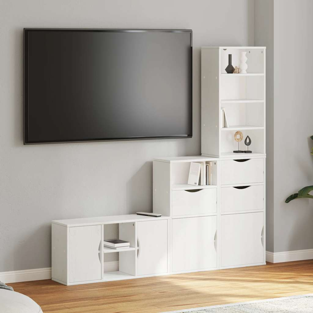 Ein an der Wand montierter Fernseher über weißen Aufbewahrungseinheiten. Die Einheiten haben Türen, Schubladen und Regale. Dekorative Gegenstände sind ausgestellt.