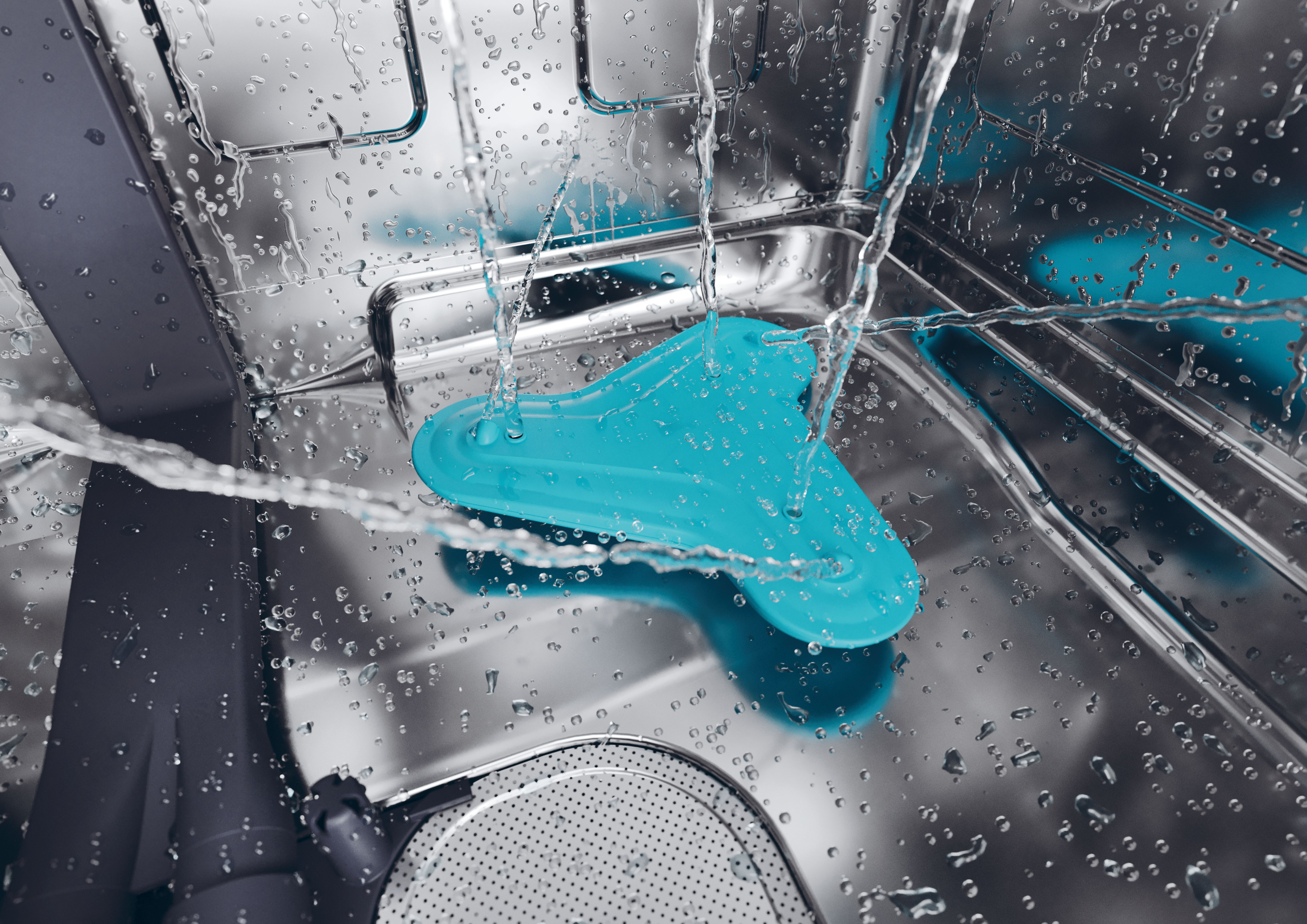 Dentro de un lavavajillas, el agua fluye sobre una pieza de plástico azul. Se ven rejillas metálicas y gotas.