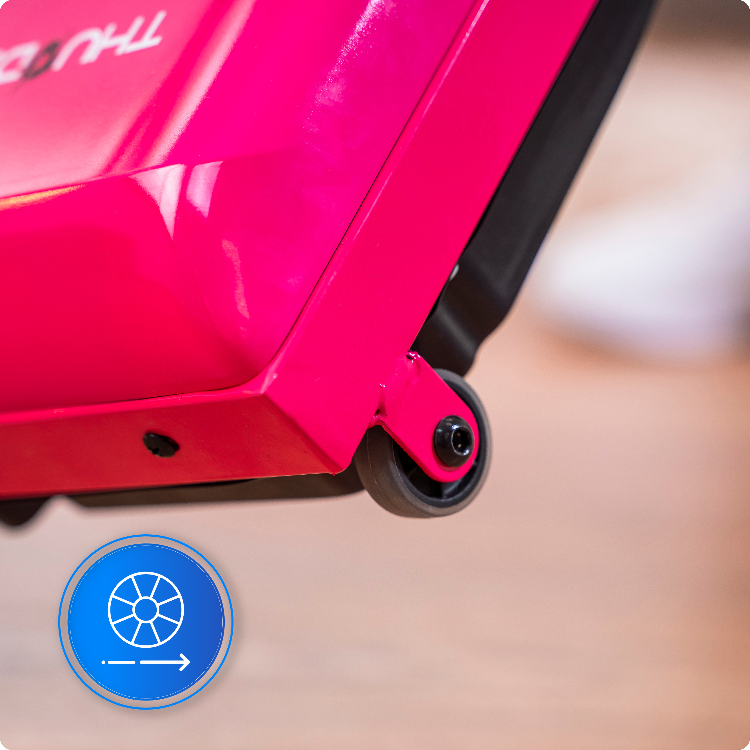 Zbliżenie różowego przedmiotu z czarnym kołem. Niebieska ikona z kołem i strzałką w rogu. Tło jest rozmyte.