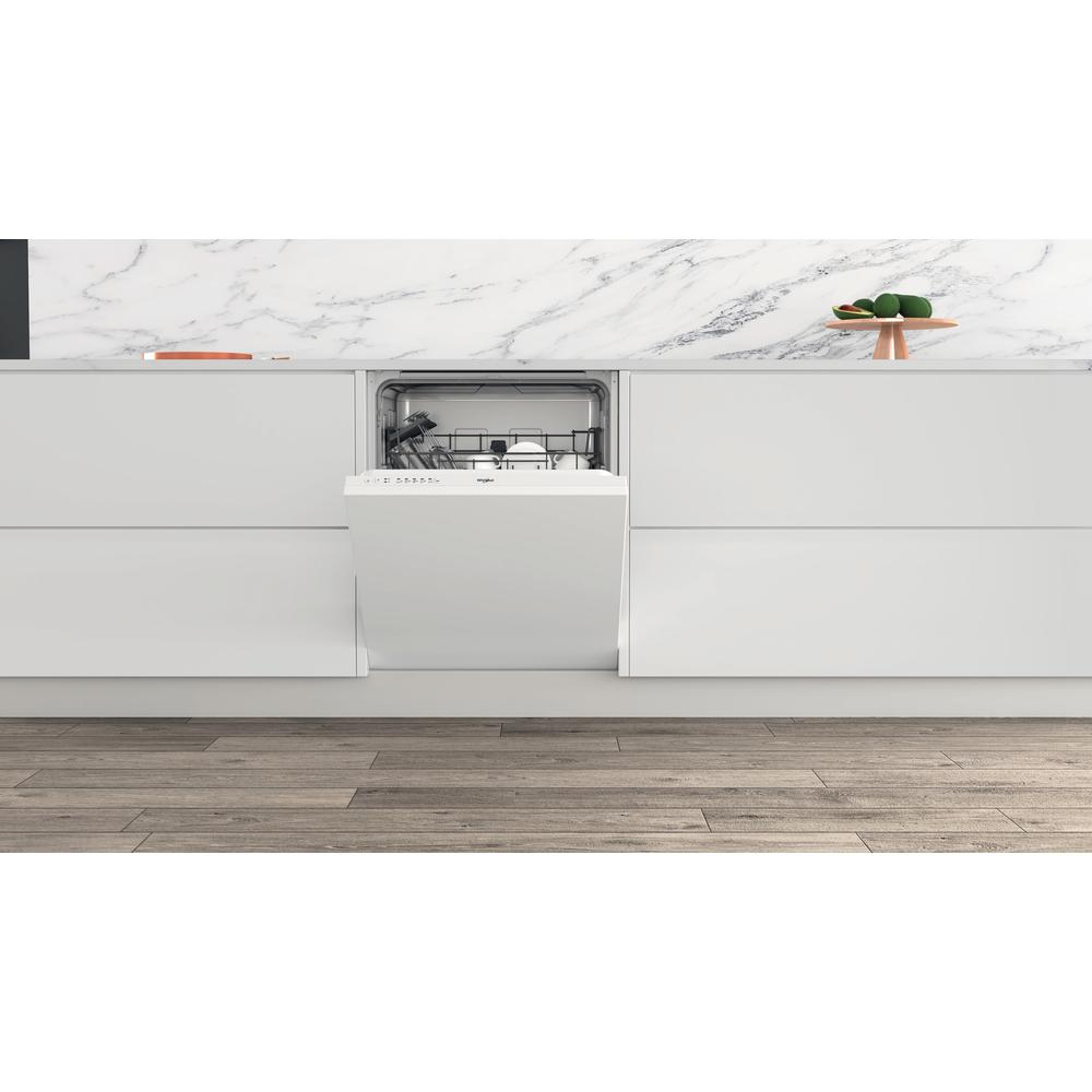 Una lavastoviglie bianca è aperta in una cucina moderna. Pavimento in legno, armadi bianchi e piano in marmo.