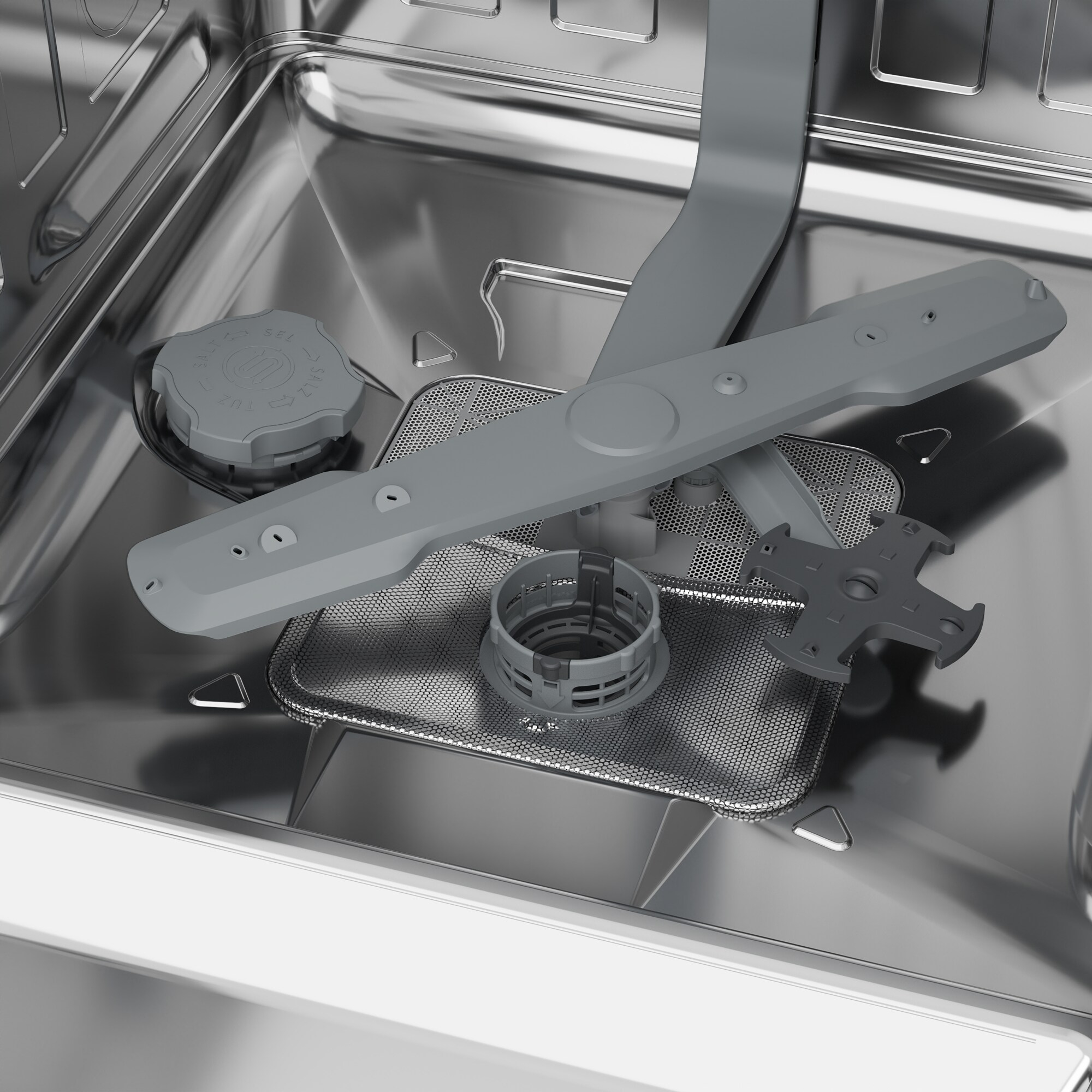 Intérieur d'un lave-vaisselle. Bras de pulvérisation gris, filtre et réservoir à sel. Intérieur en acier inoxydable. Focus sur les composants.