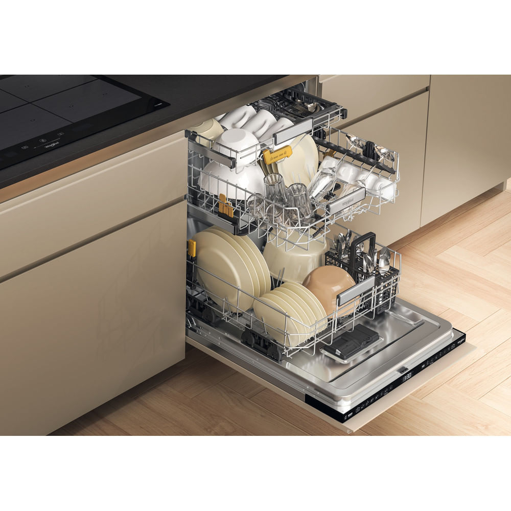 Un lavavajillas abierto lleno de platos, vasos y cubiertos. El lavavajillas está integrado en una cocina moderna con gabinetes beige.