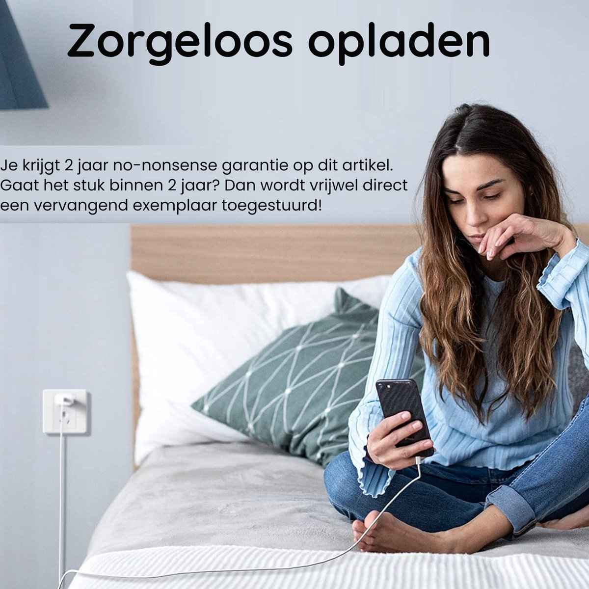 Vrouw op bed met telefoon, aan het opladen. Tekst: Zorgeloos opladen, 2 jaar garantie. Stopcontact in de muur.