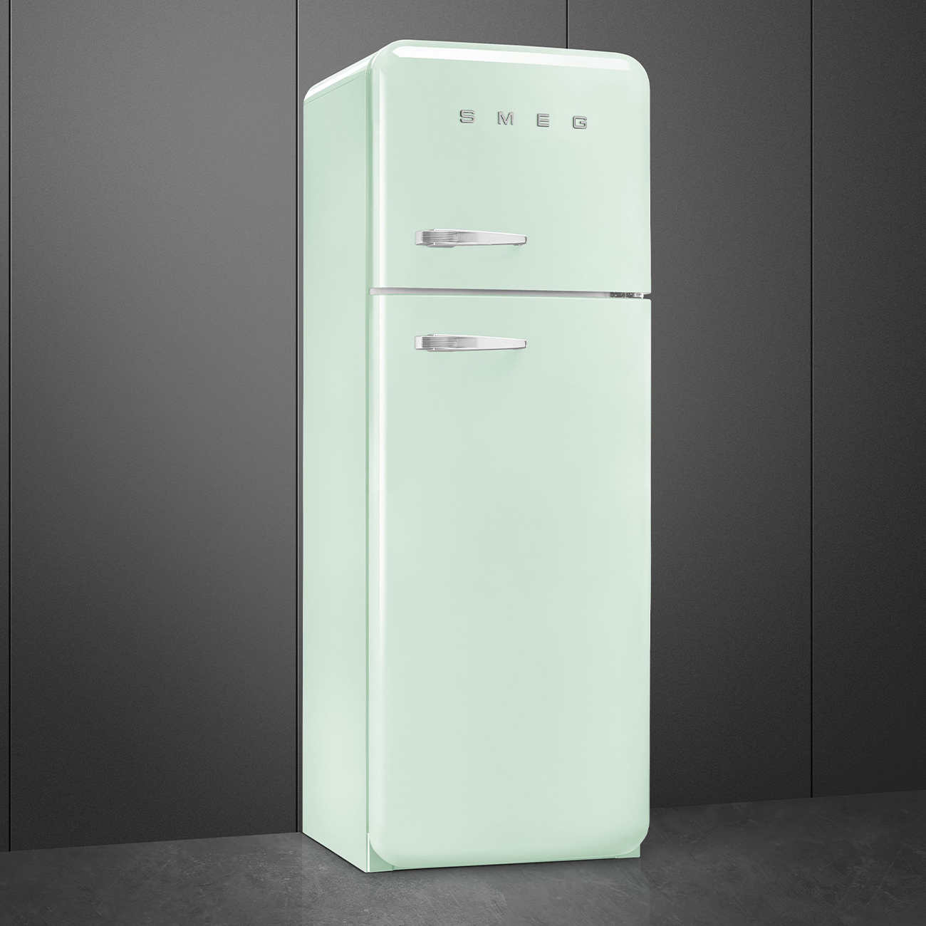 Un frigorifero SMEG verde menta è posto contro uno sfondo grigio scuro. Ha due porte, maniglie argentate e il logo SMEG in alto.