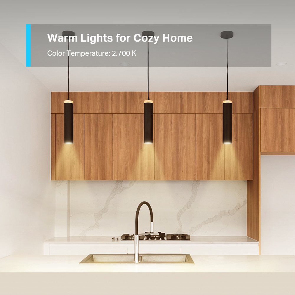 Küchenszene mit drei Pendelleuchten. Holzkästen, ein Waschbecken und eine Arbeitsplatte sind sichtbar. Der Text lautet: 'Warme Lichter für ein gemütliches Zuhause'.