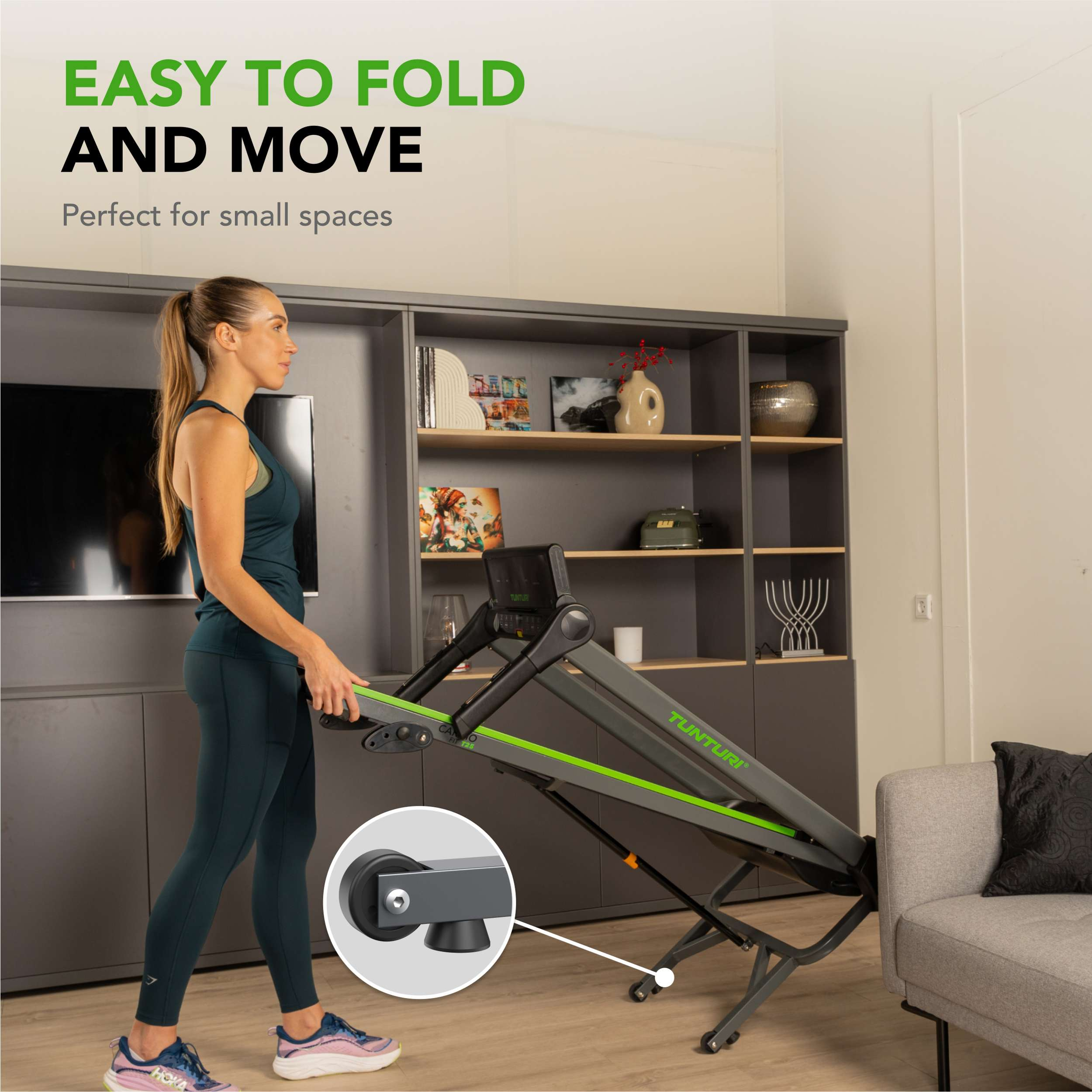 Vrouw vouwt een trainingsmachine binnen. Grijs en groene machine, vrouw in sportkleding. Grijze kast en bank.