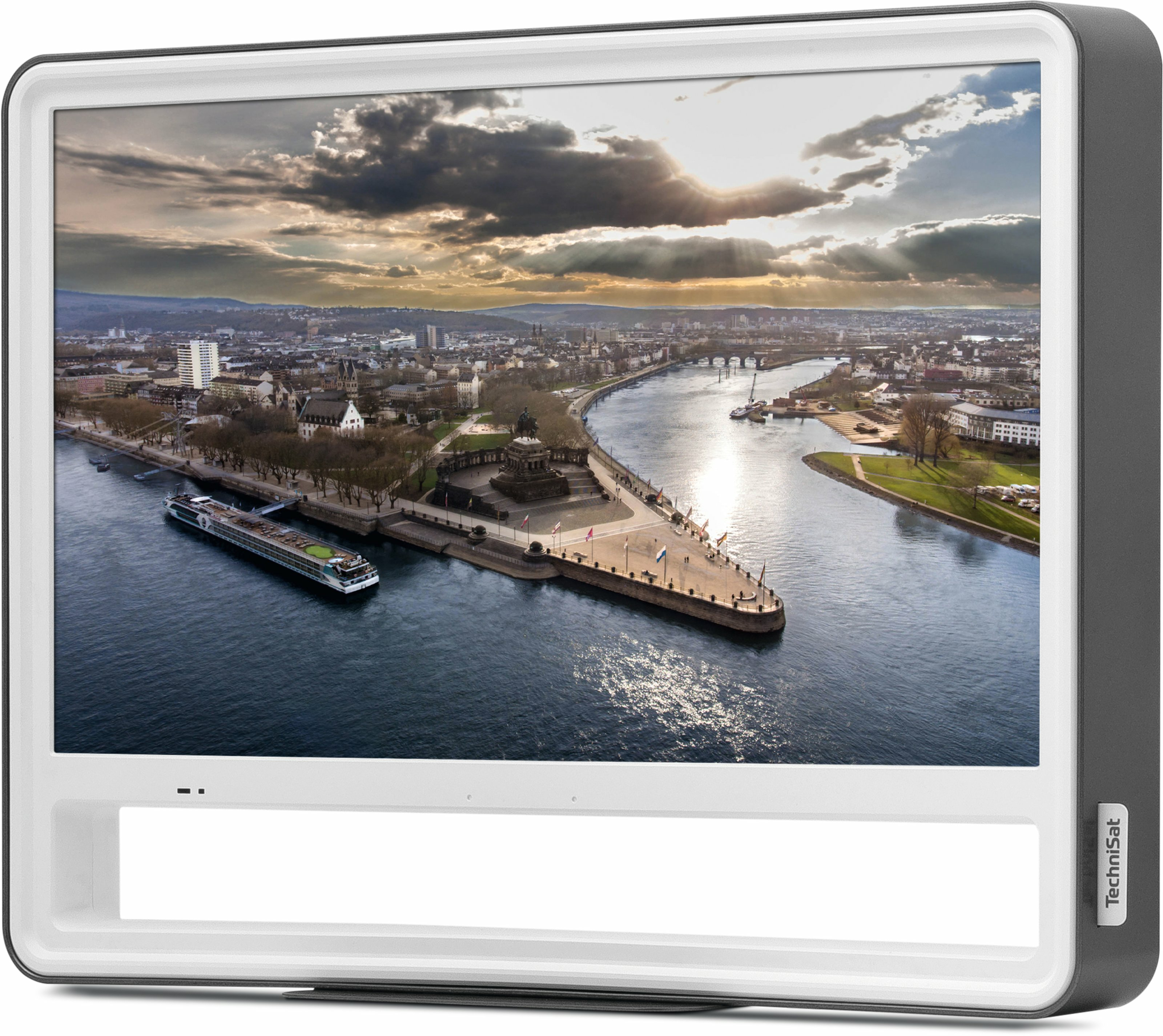 Ekran wyświetla pejzaż miejski z rzeką. Widoczne są łódź, budynki i most. Niebo jest zachmurzone.