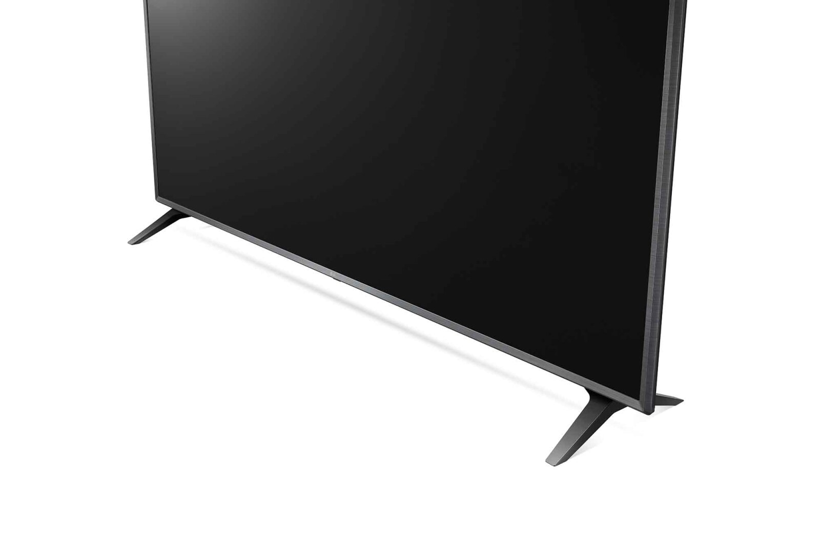Un televisor de pantalla plana negra está en ángulo hacia la derecha, con dos patas grises. El fondo es blanco.