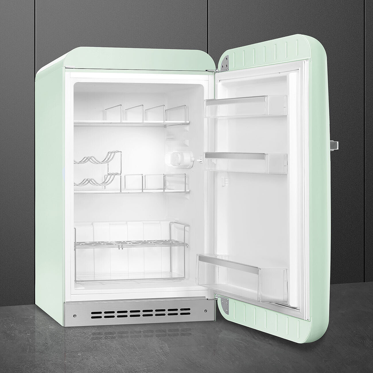 Un refrigerador retro verde menta abierto con el interior vacío. Se ven estantes y compartimentos. La puerta está entreabierta.