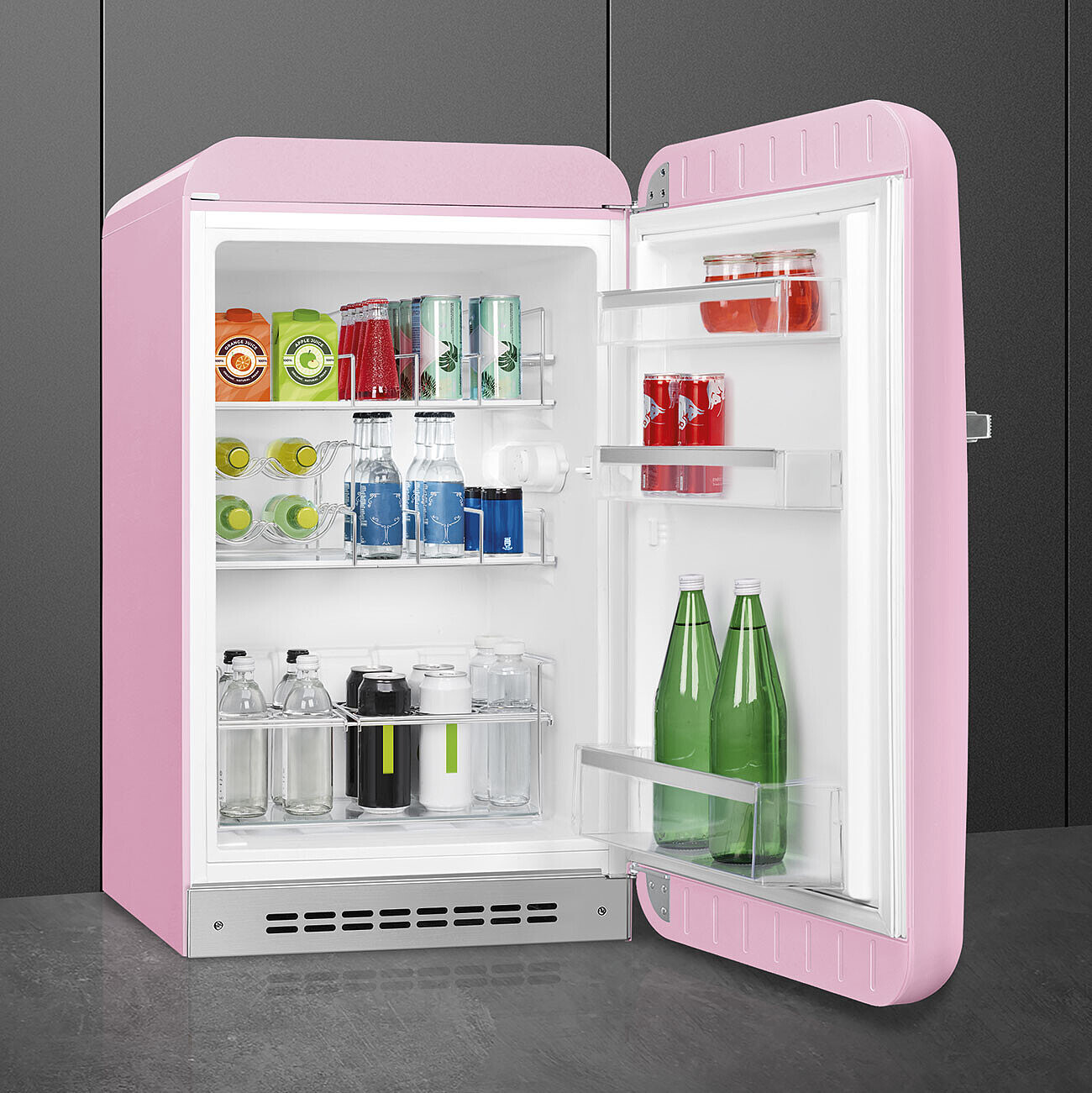 Un refrigerador rosa retro está abierto, revelando bebidas. Dentro hay latas, botellas y frascos llenos de varias bebidas.
