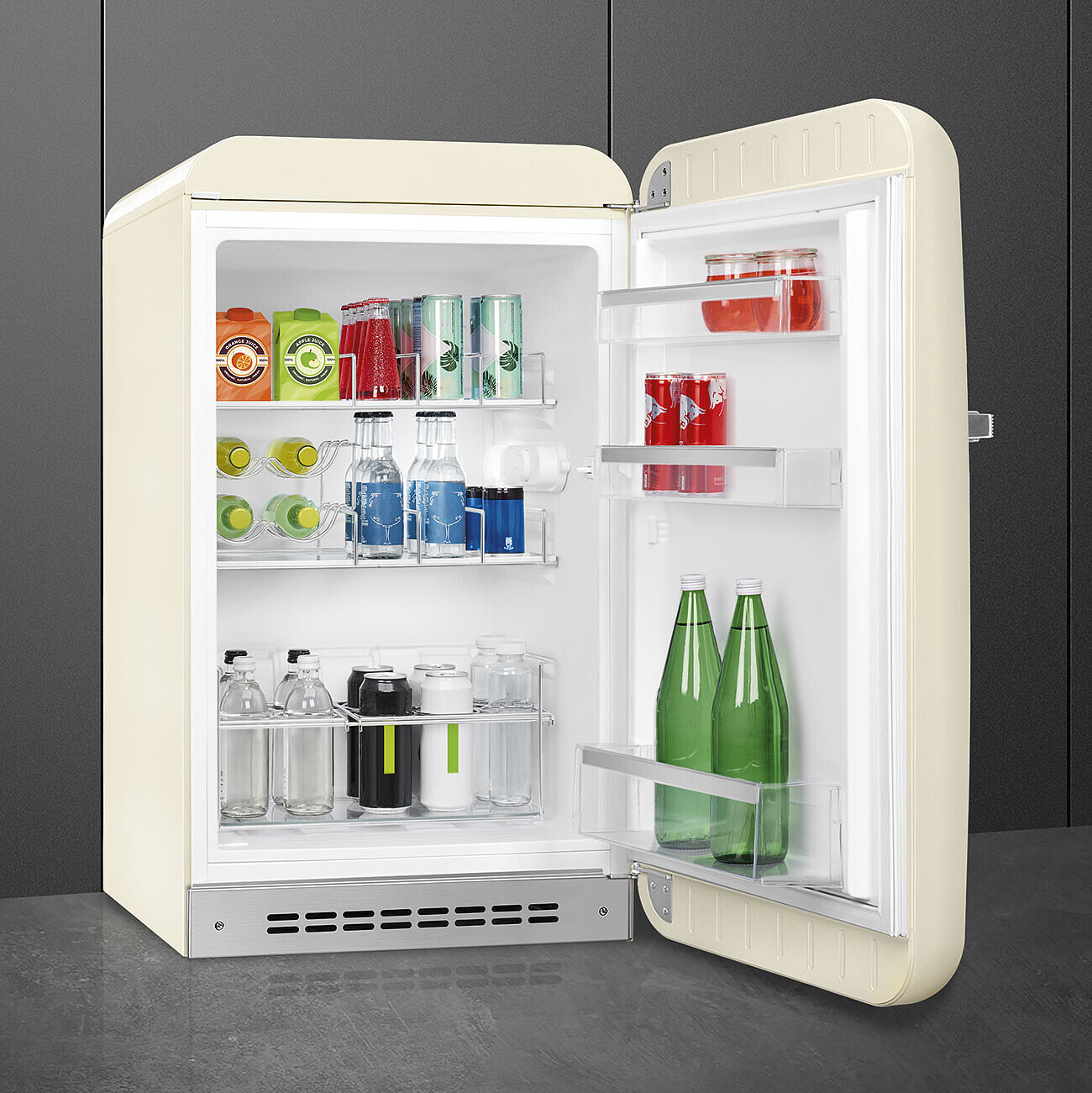 Un refrigerador retro color crema con la puerta abierta. Dentro hay bebidas como cajas de jugo, refrescos y botellas de agua.