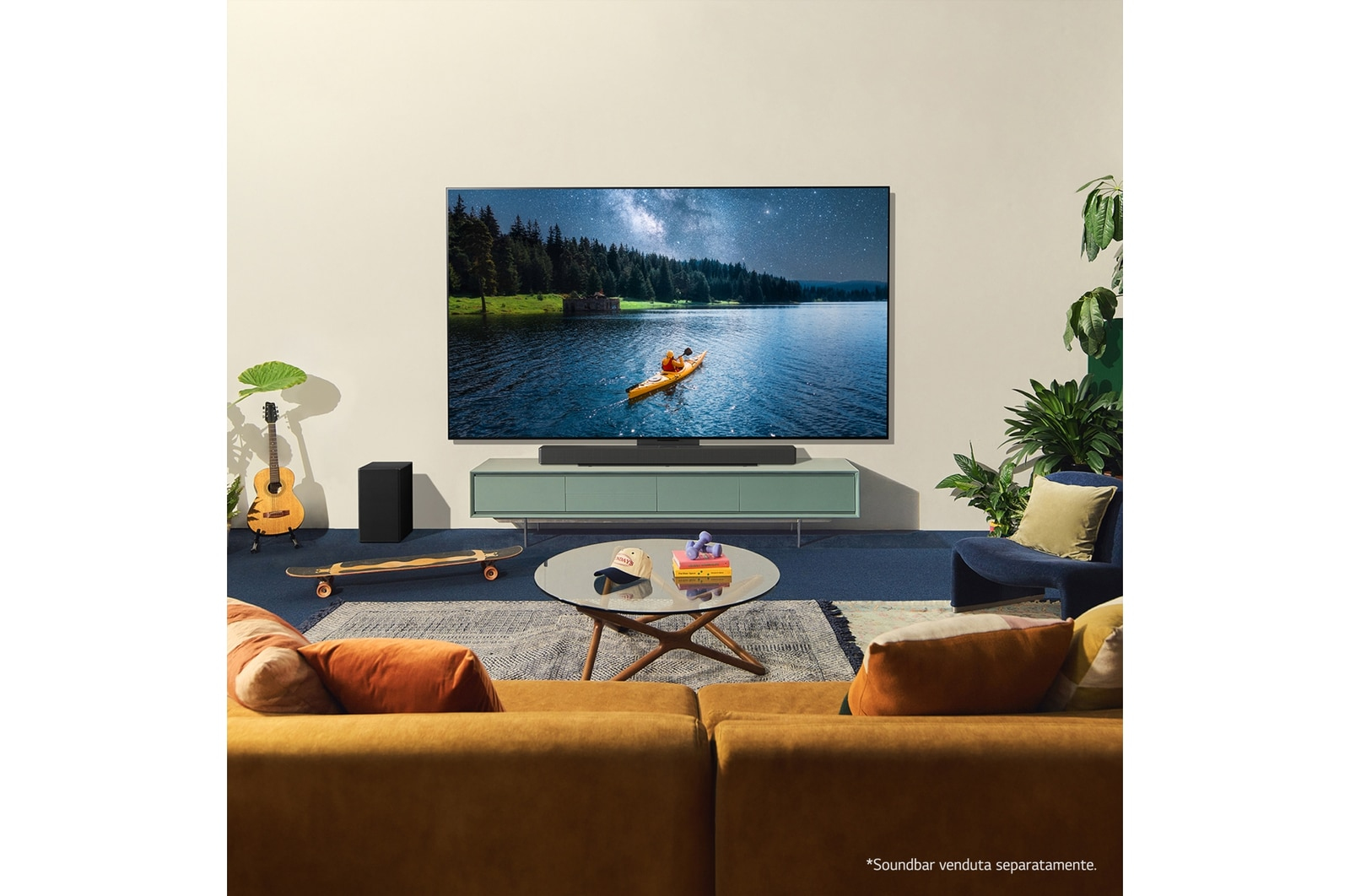 Wohnzimmer mit Fernseher, der einen Kajakfahrer zeigt. Enthält Sofa, Couchtisch, Pflanzen, Gitarre und Skateboard.
