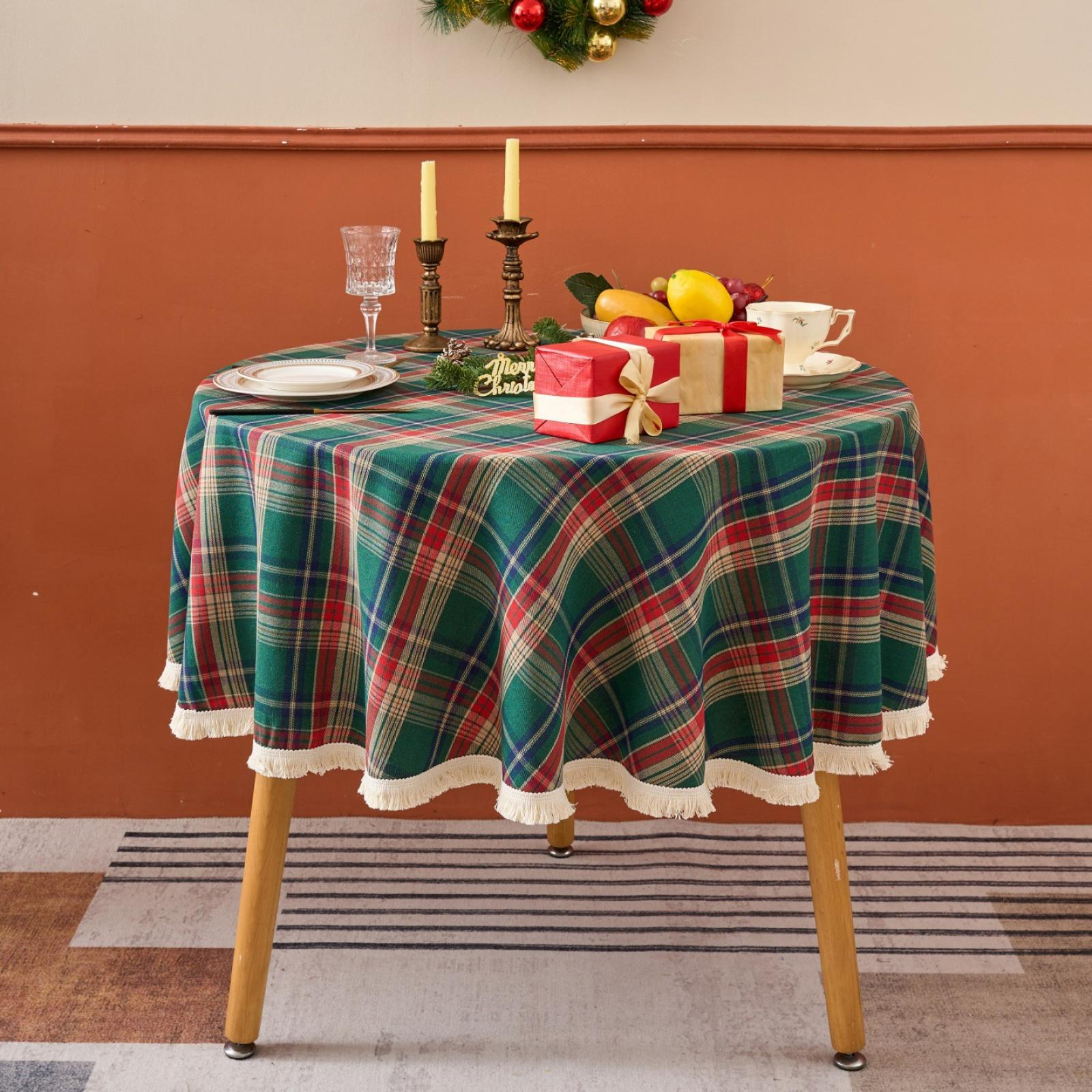 Weihnachtstisch mit karierter Tischdecke, Geschenken, Kerzen, Früchten und einer Teetasse. Oben hängt ein Kranz.