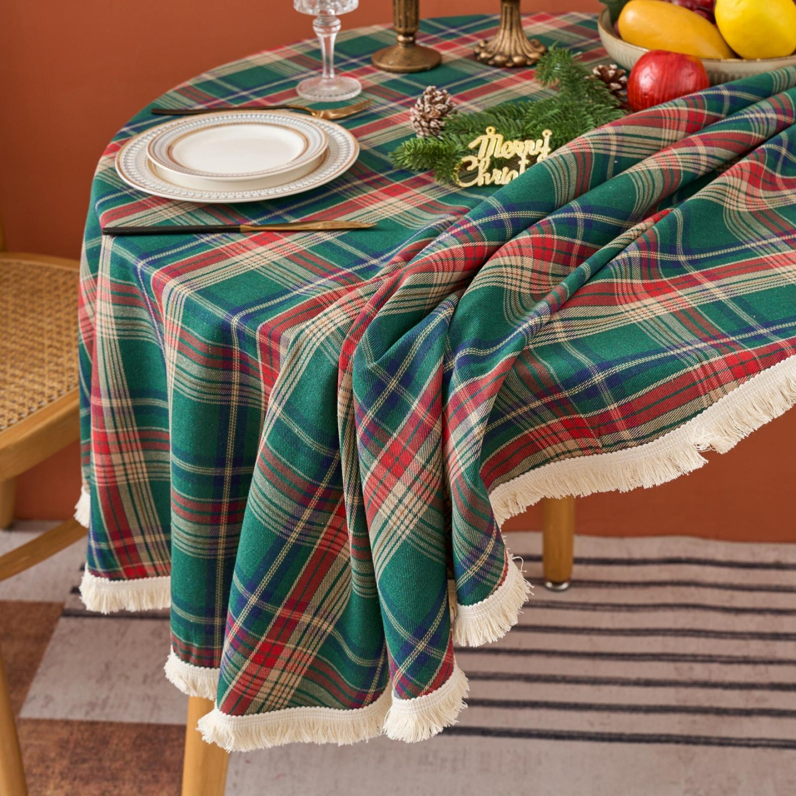 Ein Tisch mit grüner karierter Tischdecke ist für Weihnachten gedeckt. Enthält Teller, Gläser und Obst. Der Tisch steht auf einem Teppich.