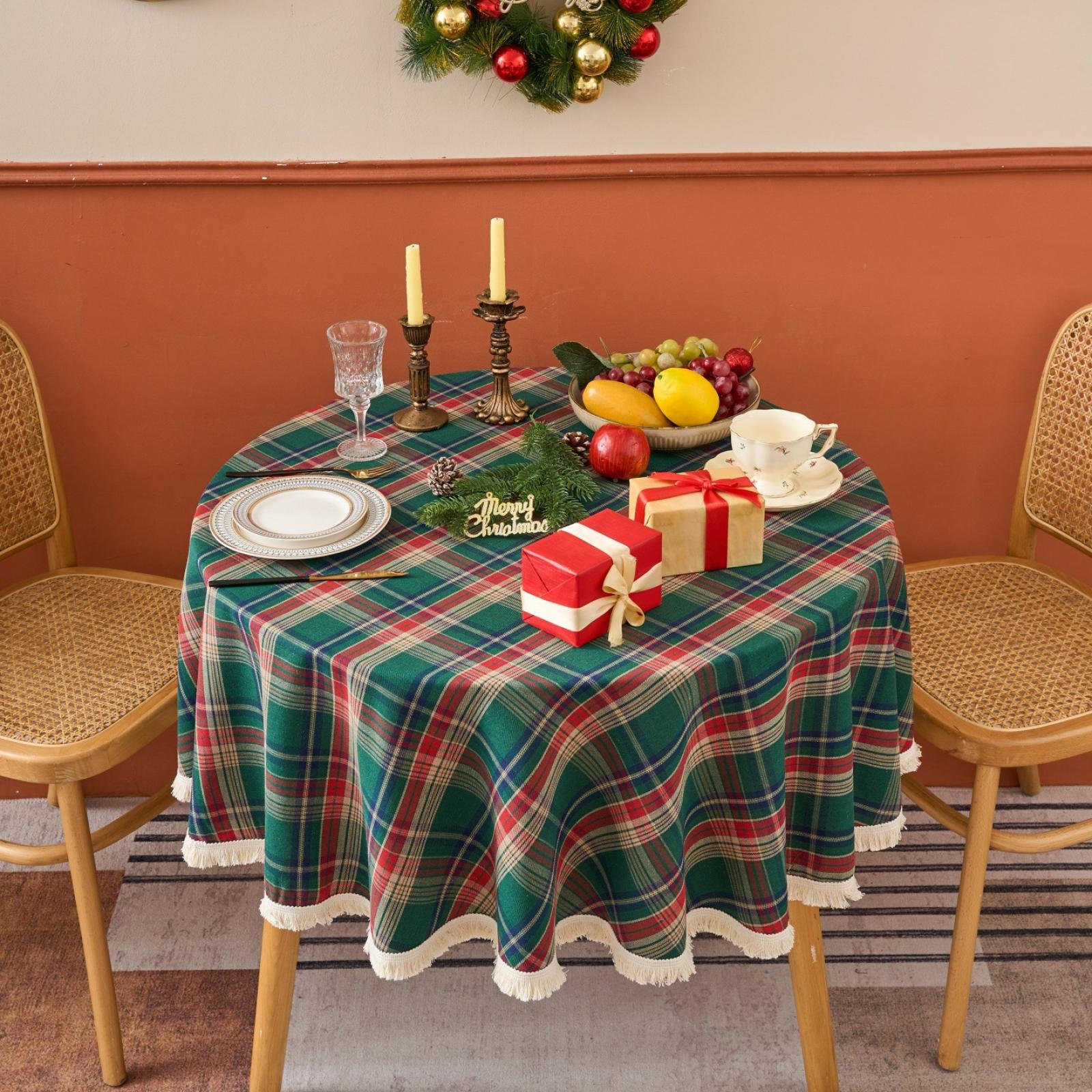 Ein festlicher Tisch mit grün karierter Tischdecke, Geschenken, Obst, Kerzen und einem Kranz. Zwei Stühle flankieren den Tisch.