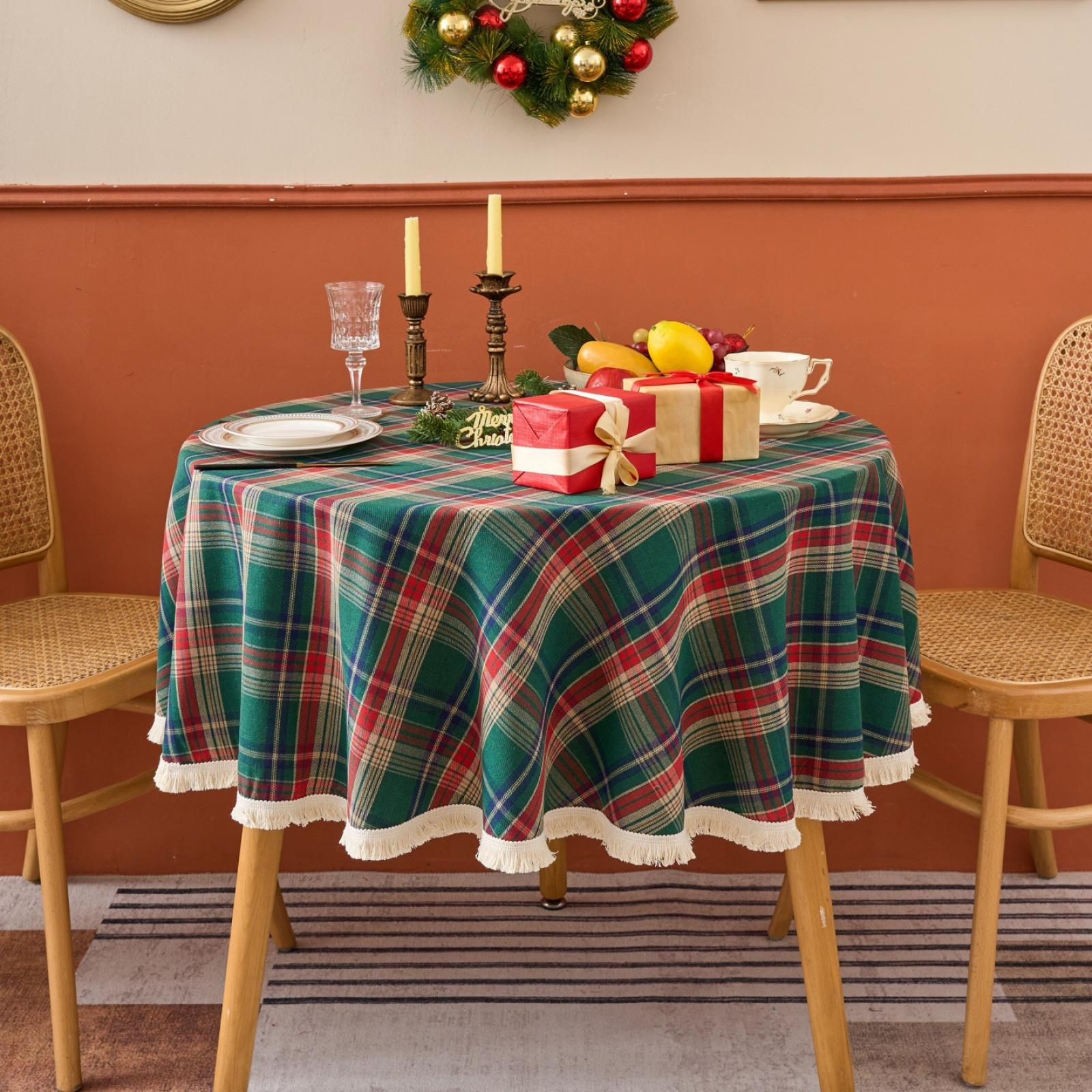 Ein runder Tisch mit einer grün karierten Tischdecke. Geschenke, Obst und Kerzen stehen auf dem Tisch. Zwei Stühle stehen neben dem Tisch.