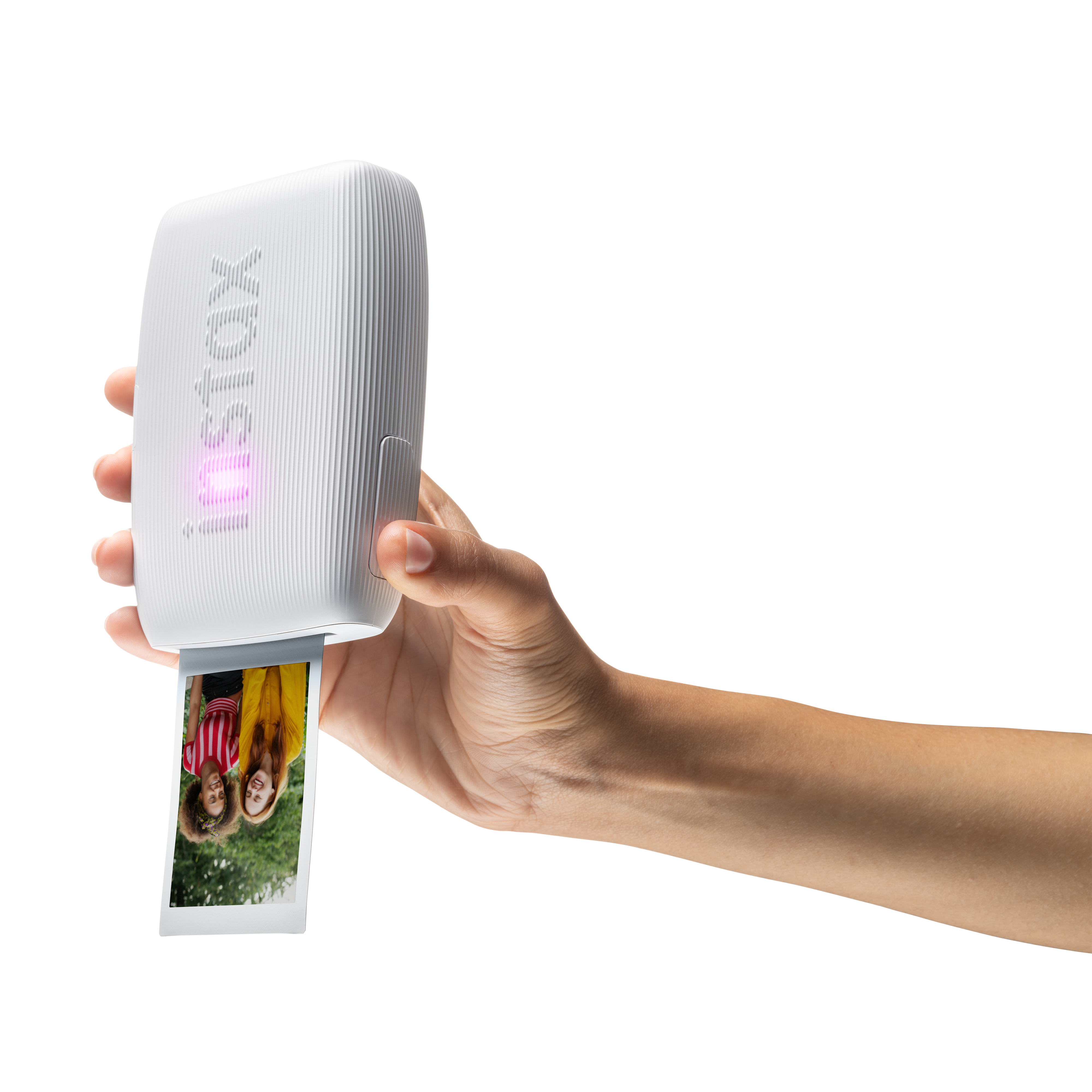Eine Hand hält einen weißen Instax-Drucker, aus dem ein Foto kommt. Das Foto zeigt zwei Frauen.