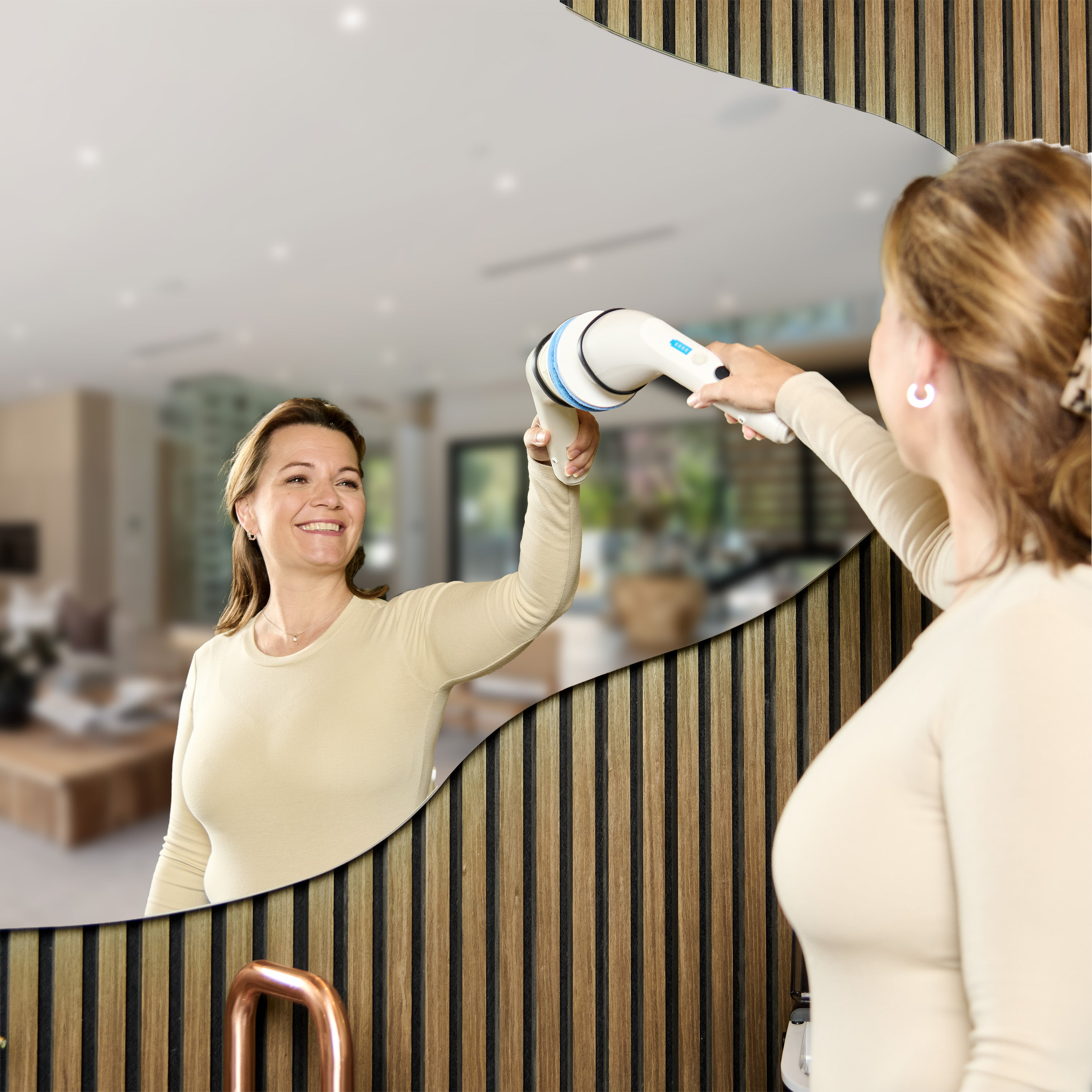 Woman using a massage device in front of a mirror. The mirror is framed with wooden panels. 