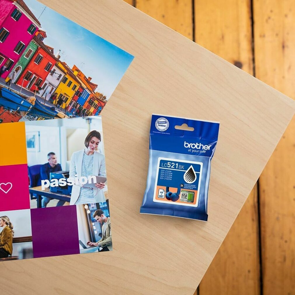 Wkład atramentowy Brother LC521BK i broszura z kolorowymi budynkami i ludźmi pracującymi na drewnianej powierzchni.