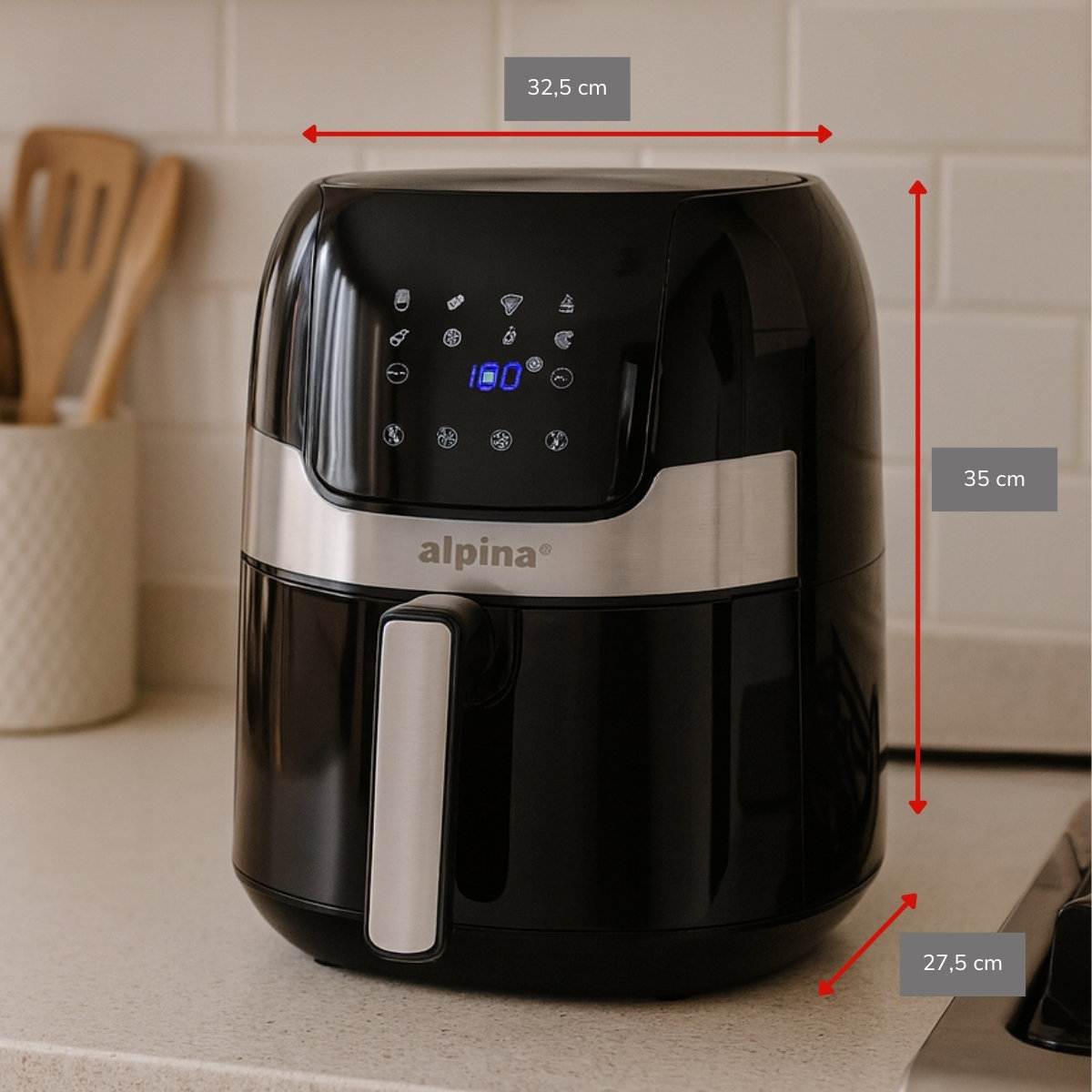 Zwarte Alpina airfryer op een aanrecht. Het heeft een digitaal display met 100. Afmetingen: 32,5x35x27,5 cm. Achtergrond toont keukenartikelen.