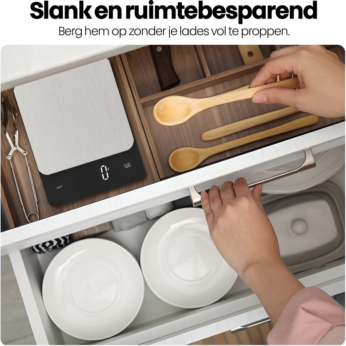 A kitchen drawer is opened, revealing white plates, wooden spoons, and a digital scale. A hand is pulling the drawer.