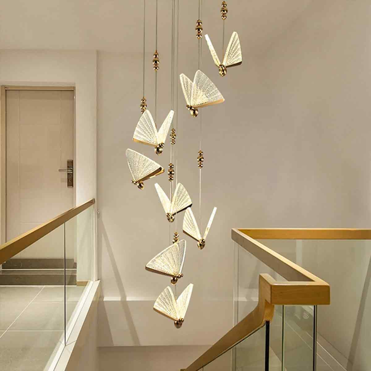 Eine moderne Treppe mit schmetterlingsförmigen Lichtern, die von der Decke hängen. Holzhandläufe und Glasscheiben sind sichtbar.