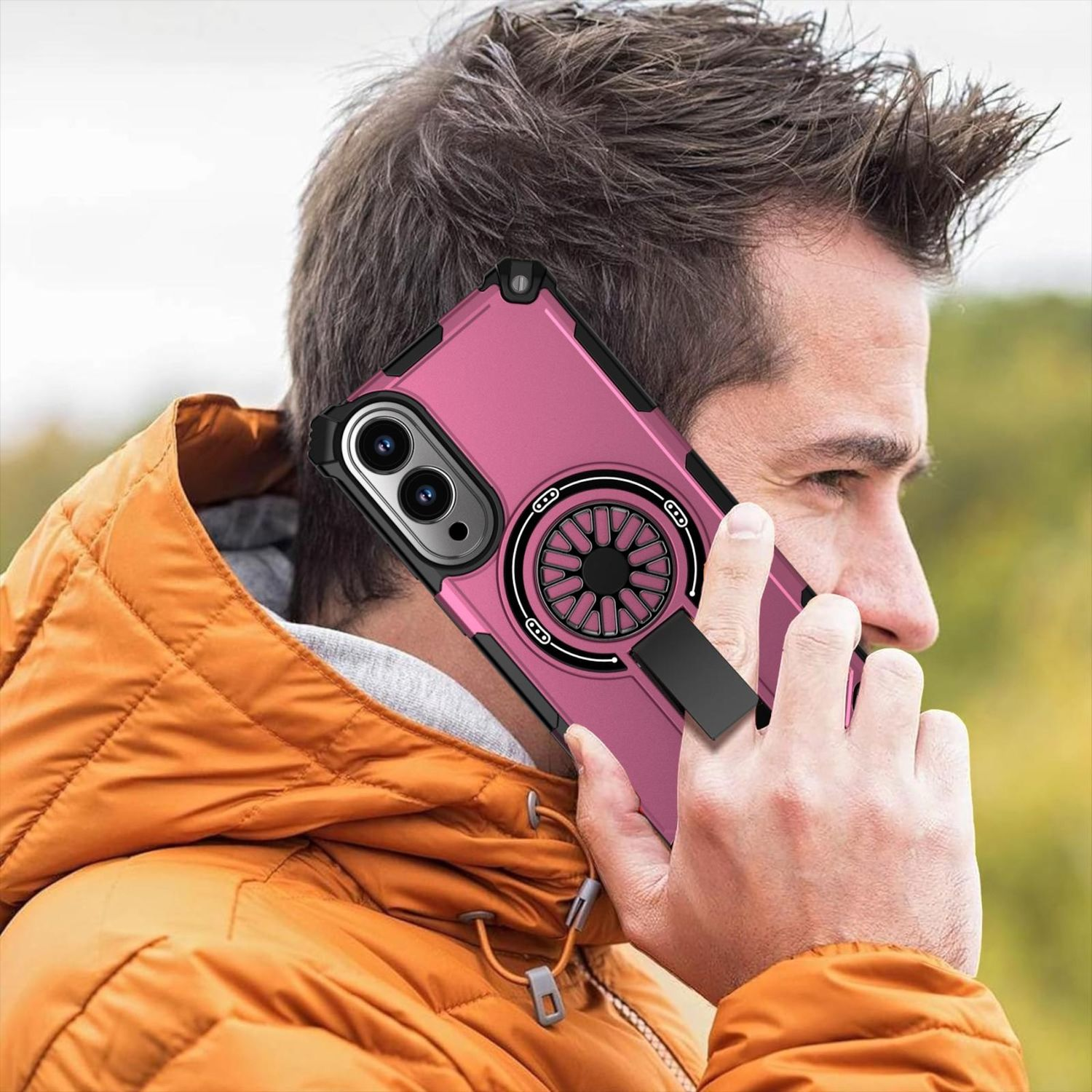 Mann mit orangefarbener Jacke hält ein pinkfarbenes Telefon mit schwarzem Ringhalter. Das Telefon ist an seinem Ohr.