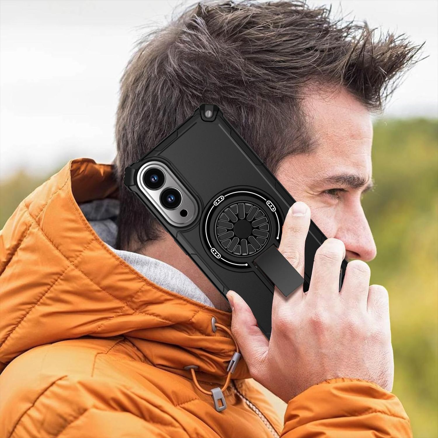 Ein Mann benutzt ein Telefon. Das Telefon hat eine schwarze Hülle mit einem Ringhalter. Er trägt eine orangefarbene Jacke.