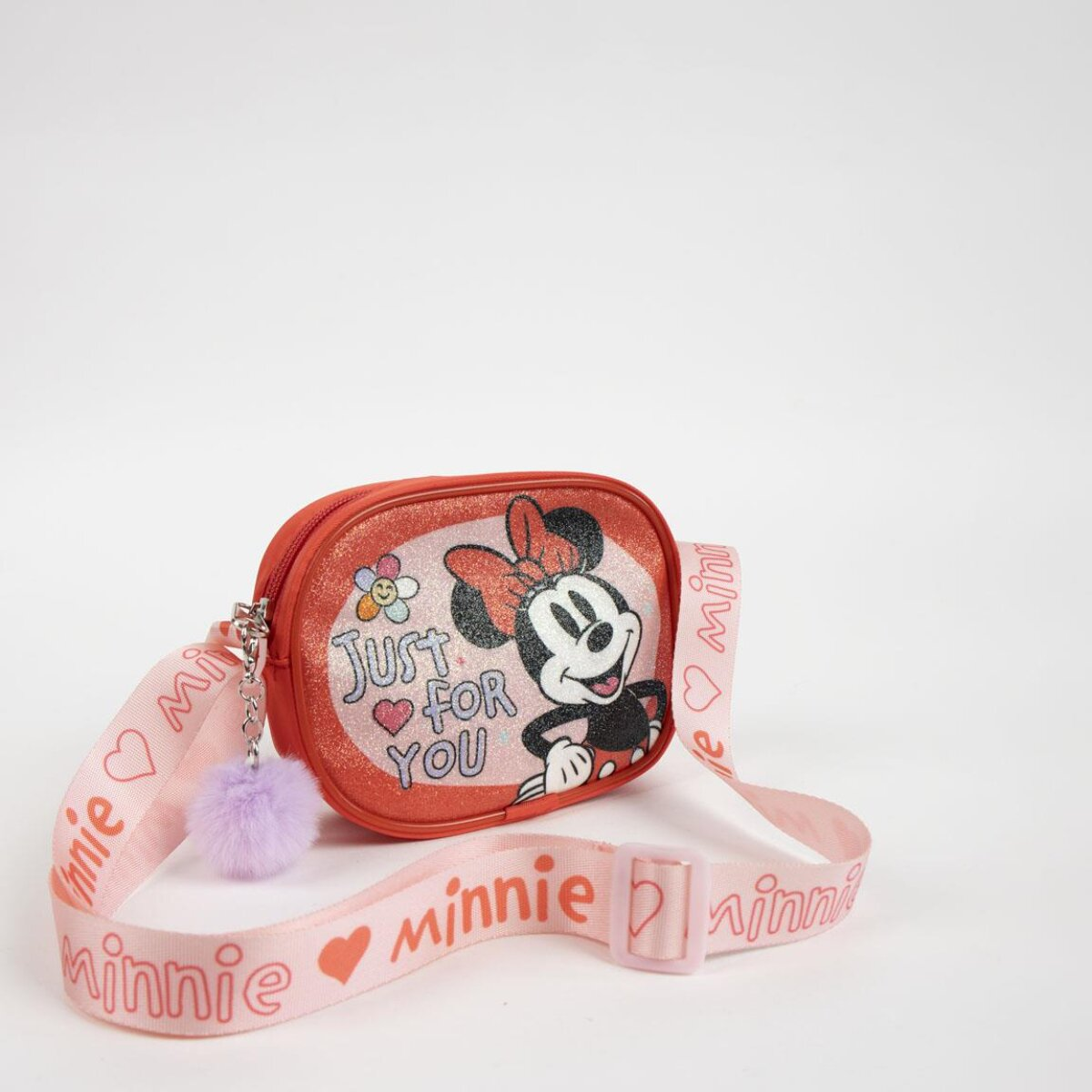 Bolso cruzado rojo de Minnie Mouse con correa rosa. La bolsa dice 'Just for You' y tiene un adorno de pompón.