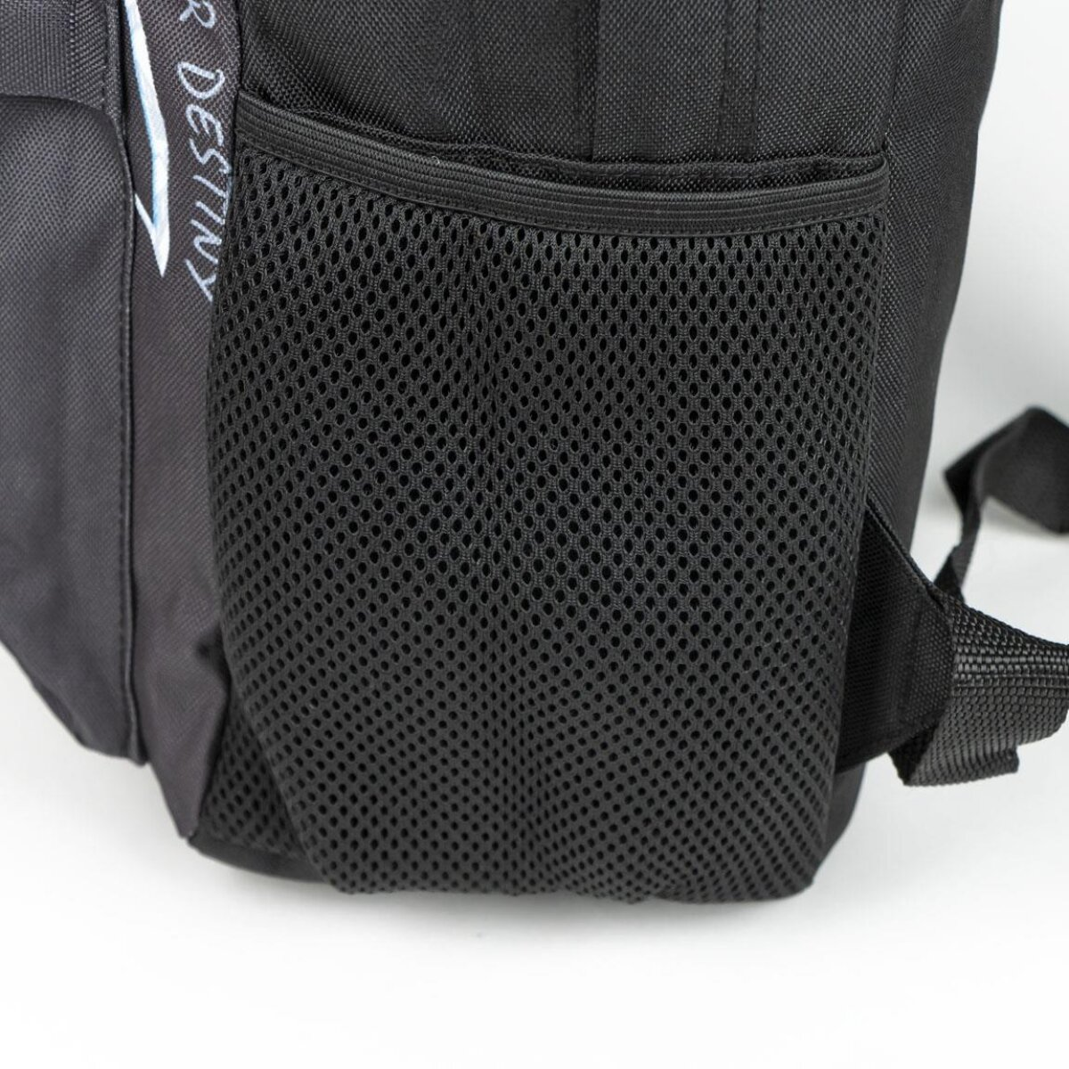 Mochila negra con bolsillo lateral de malla. La palabra "DESTINY" es visible en el lado izquierdo. Fondo blanco.