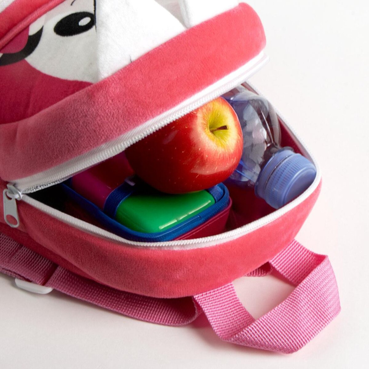 Offener pinker Rucksack mit rotem Apfel, Wasserflasche und Lunchbox. Der Rucksack hat ein Cartoon-Design. Weißer Hintergrund.