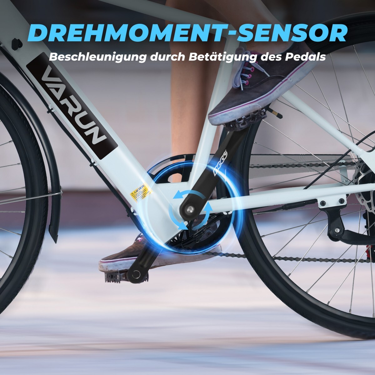 Osoba na białym rowerze, pedałuje. Rower ma napis 'VARUN' na ramie. Tekst brzmi 'DREHMOMENT-SENSOR'.