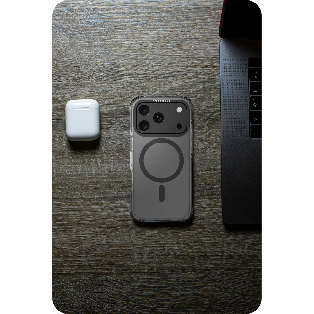 Draufsicht. iPhone in Hülle, AirPods und Laptop auf Holzoberfläche. Hülle hat MagSafe-Ring. AirPods-Hülle ist weiß.