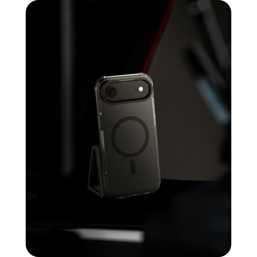 Uno smartphone nero in una custodia trasparente è su un supporto. La custodia ha un cerchio MagSafe e un ritaglio per la fotocamera. Lo sfondo è scuro.