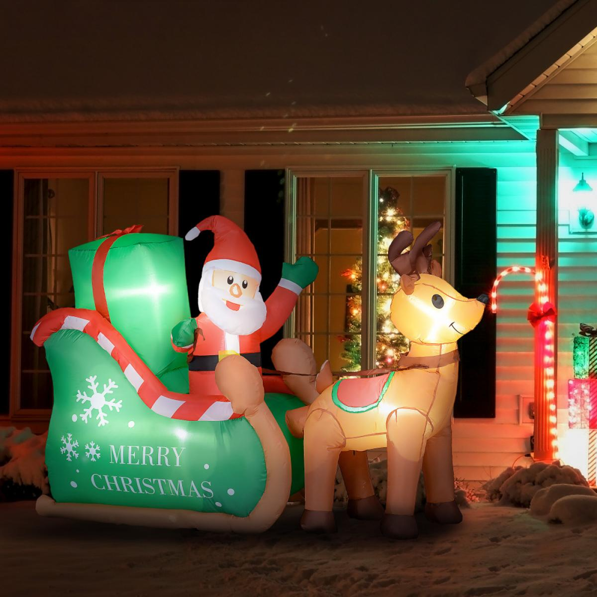 Ein aufblasbarer Weihnachtsmann auf einem Schlitten, der von einem Rentier gezogen wird, dekoriert mit Weihnachtsbeleuchtung. Schnee bedeckt den Boden.