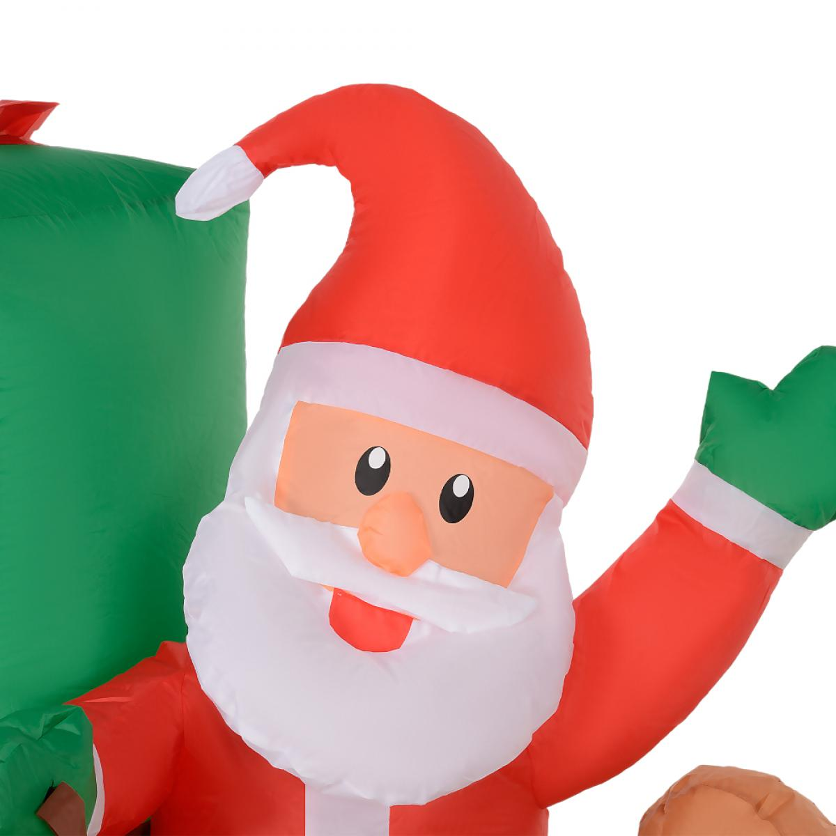 Aufblasbarer Weihnachtsmann mit rotem Hut, Anzug, weißem Bart und grünem Fäustling winkt. Große grüne Tasche im Hintergrund.