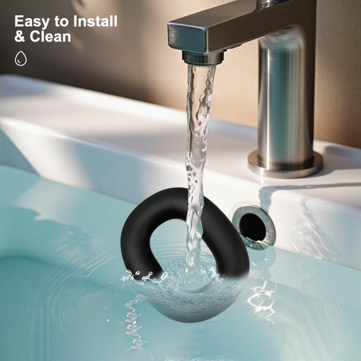 Wasser fließt aus einem Wasserhahn in ein Waschbecken. Ein schwarzer Gummiring liegt im Wasser. Text: Einfach zu installieren & reinigen.