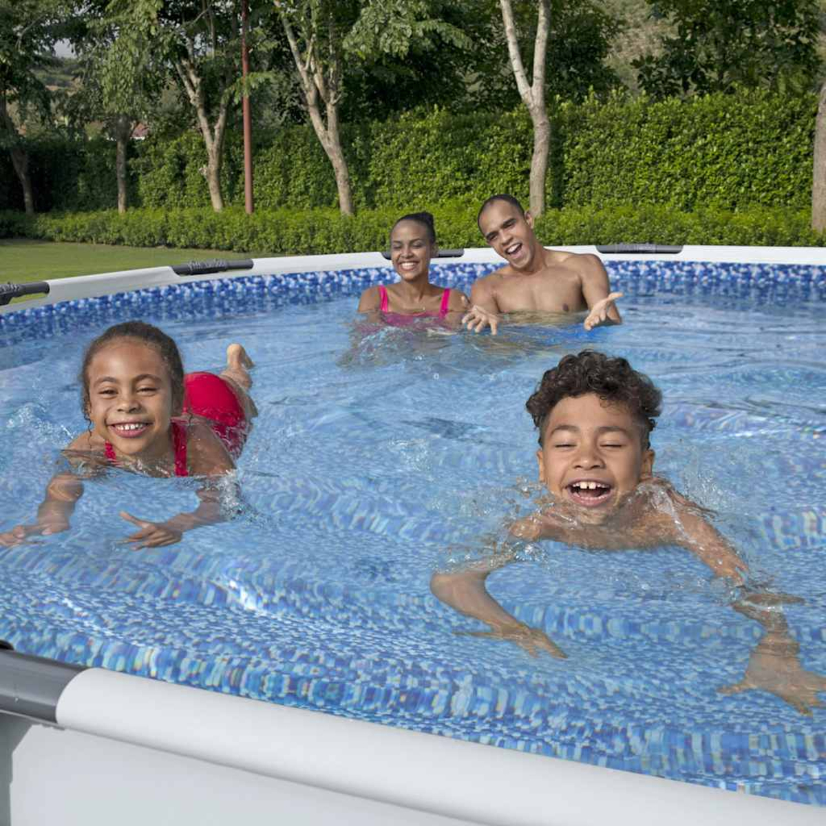 Vier Personen in einem Pool, zwei Kinder und zwei Erwachsene, alle lächeln. Bäume im Hintergrund. Blaues Mosaikbecken.