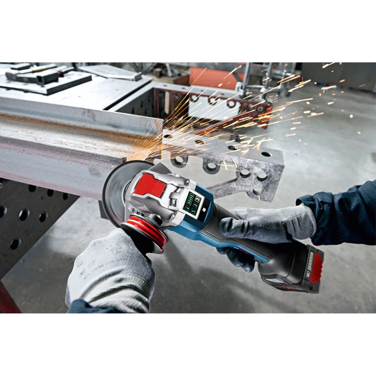 Eine Person schleift Metall mit einem Winkelschleifer, Funken fliegen. Sie tragen Handschuhe. Das Werkzeug ist blau, rot und silber.