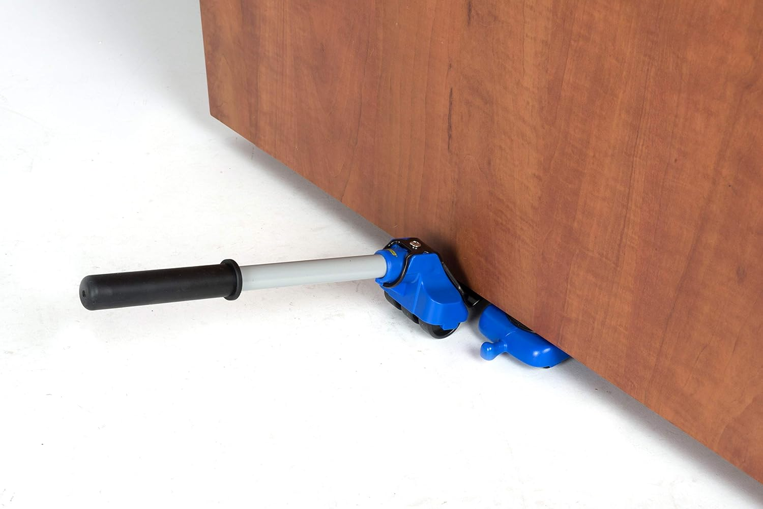 Ein blauer Möbellifter ist unter einem braunen Holzschrank verkeilt. An einem Ende befindet sich ein schwarzer Griff.