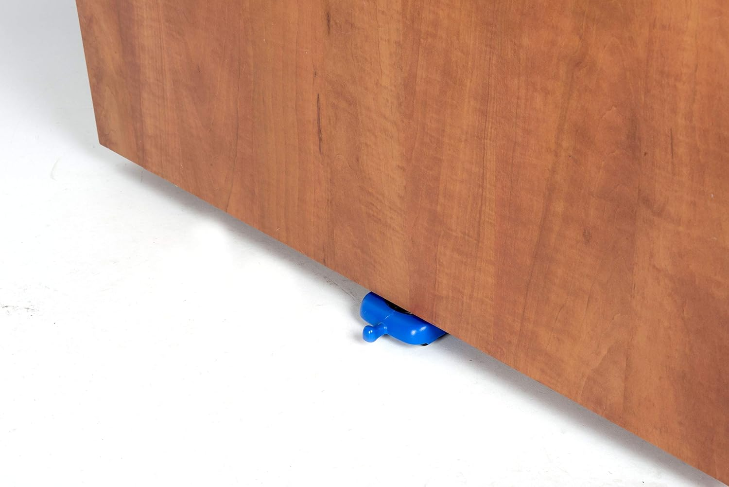 Eine Holztür wird von einem blauen Türstopper offen gehalten. Die Tür ist braun und der Hintergrund ist weiß.