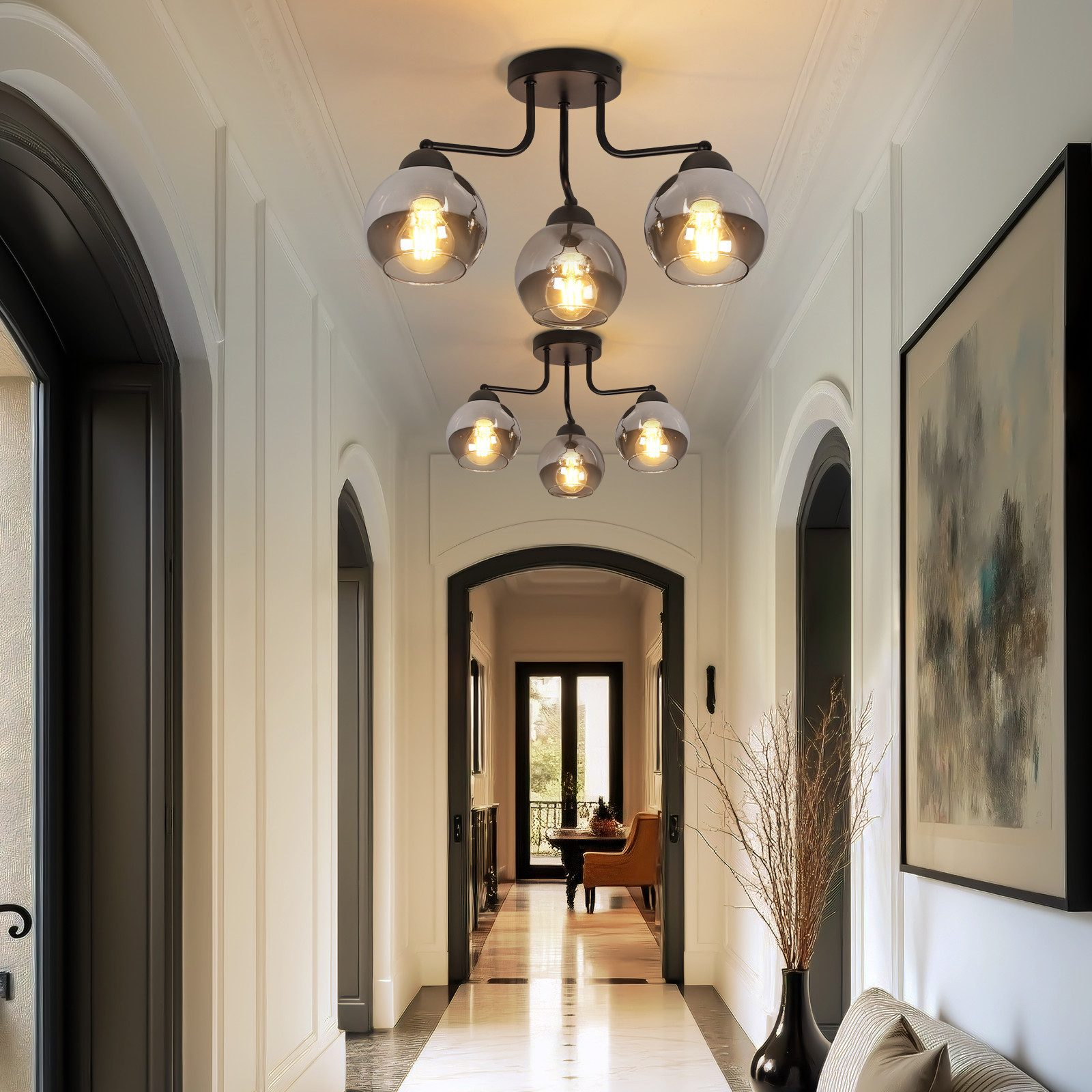 Corridoio con lampade a sospensione, porte, opere d'arte e vaso con rami. Colori neutri, design classico.
